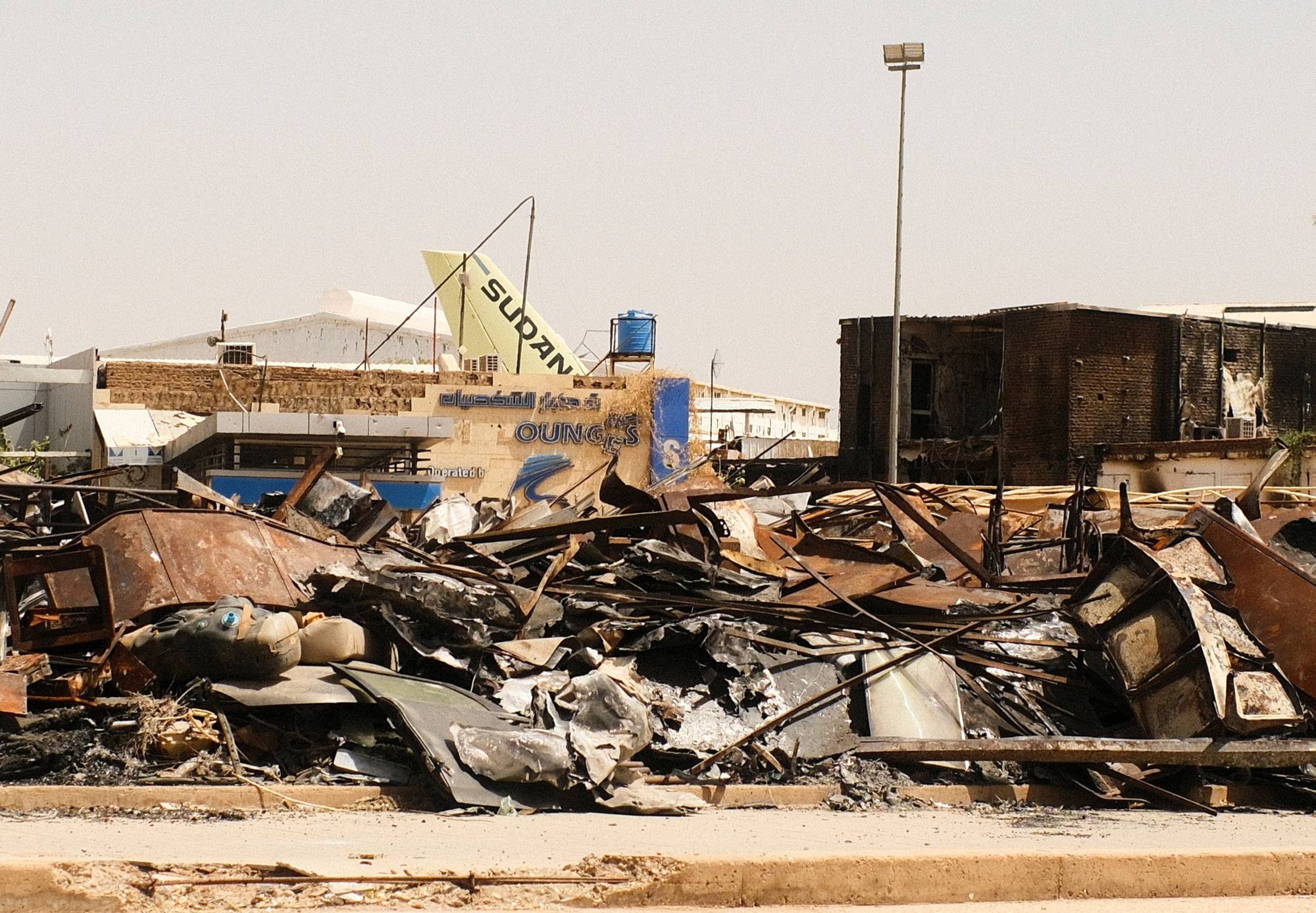 جانب من مبنى محترق وذيل طائرة تابعة لـ«الخطوط الجوية السودانية» وسط الحطام في مطار الخرطوم (أرشيفية - رويترز)