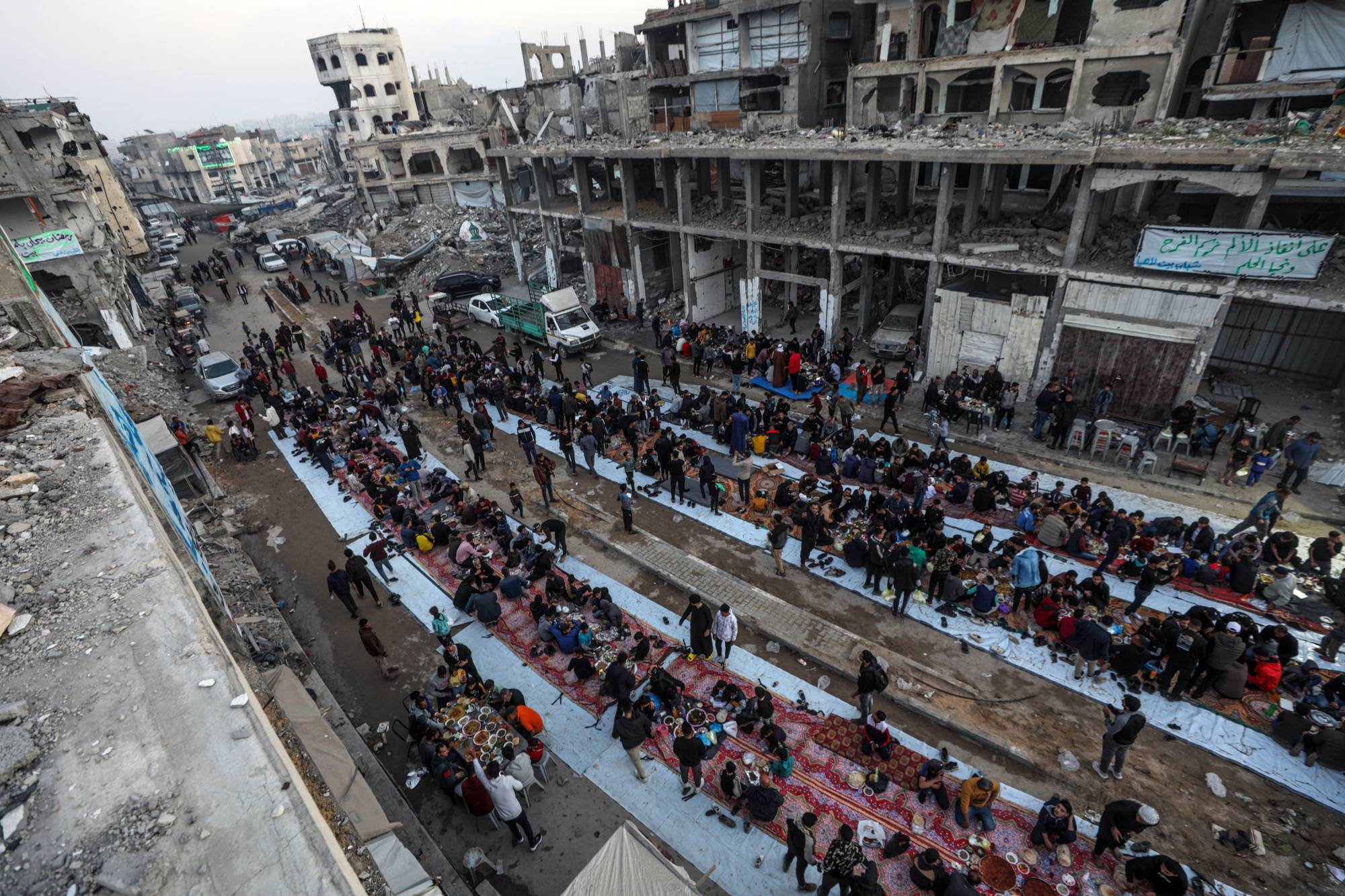 فلسطينيون متجمعون بين مبانٍ مدمَّرة في بيت لاهيا بشمال قطاع غزة لتناول طعام الإفطار الرمضاني (إ.ب.أ)