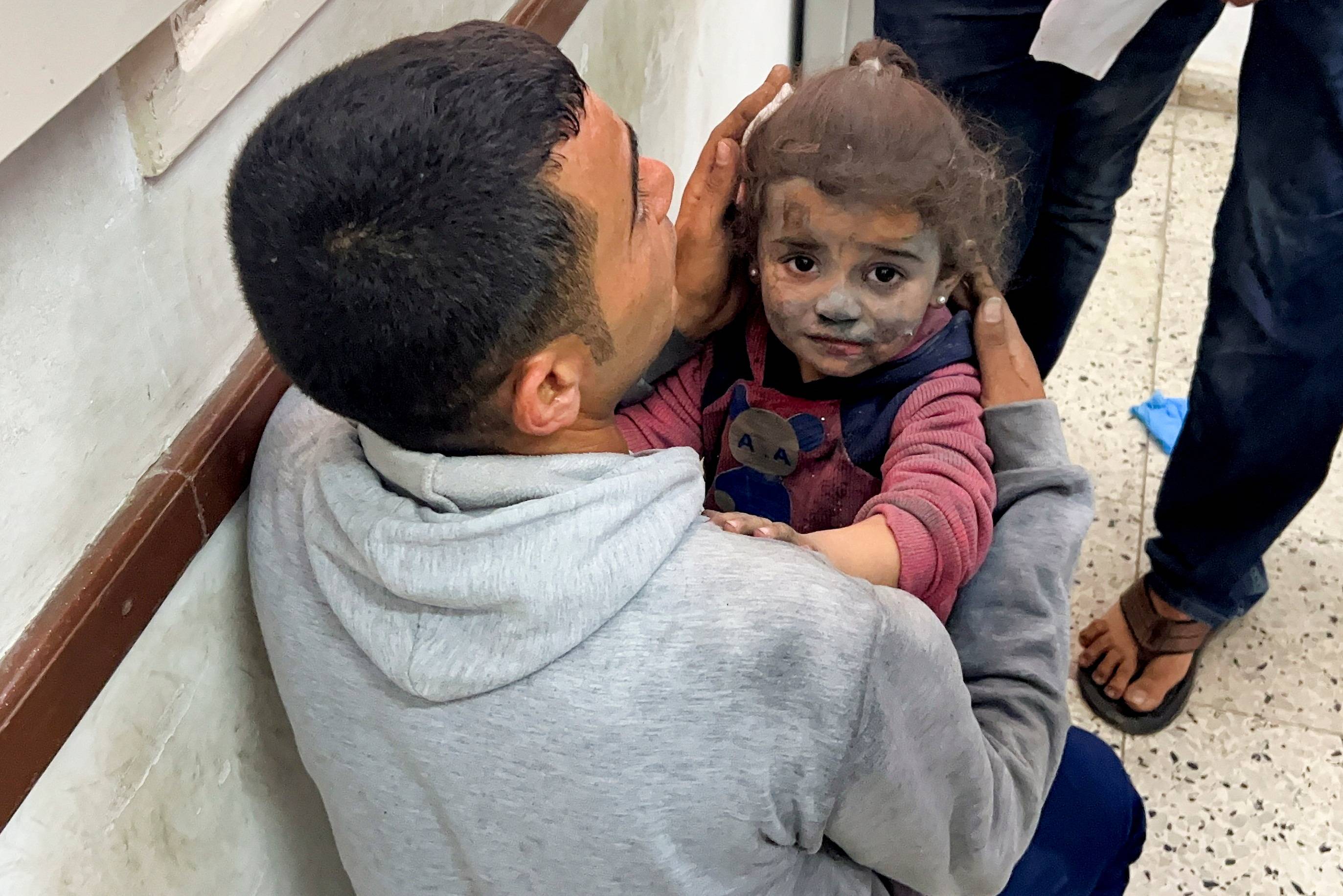 طفلة فلسطينية مصابة يحملها رجل في مستشفى بعد غارة إسرائيلية بمدينة غزة (رويترز)
