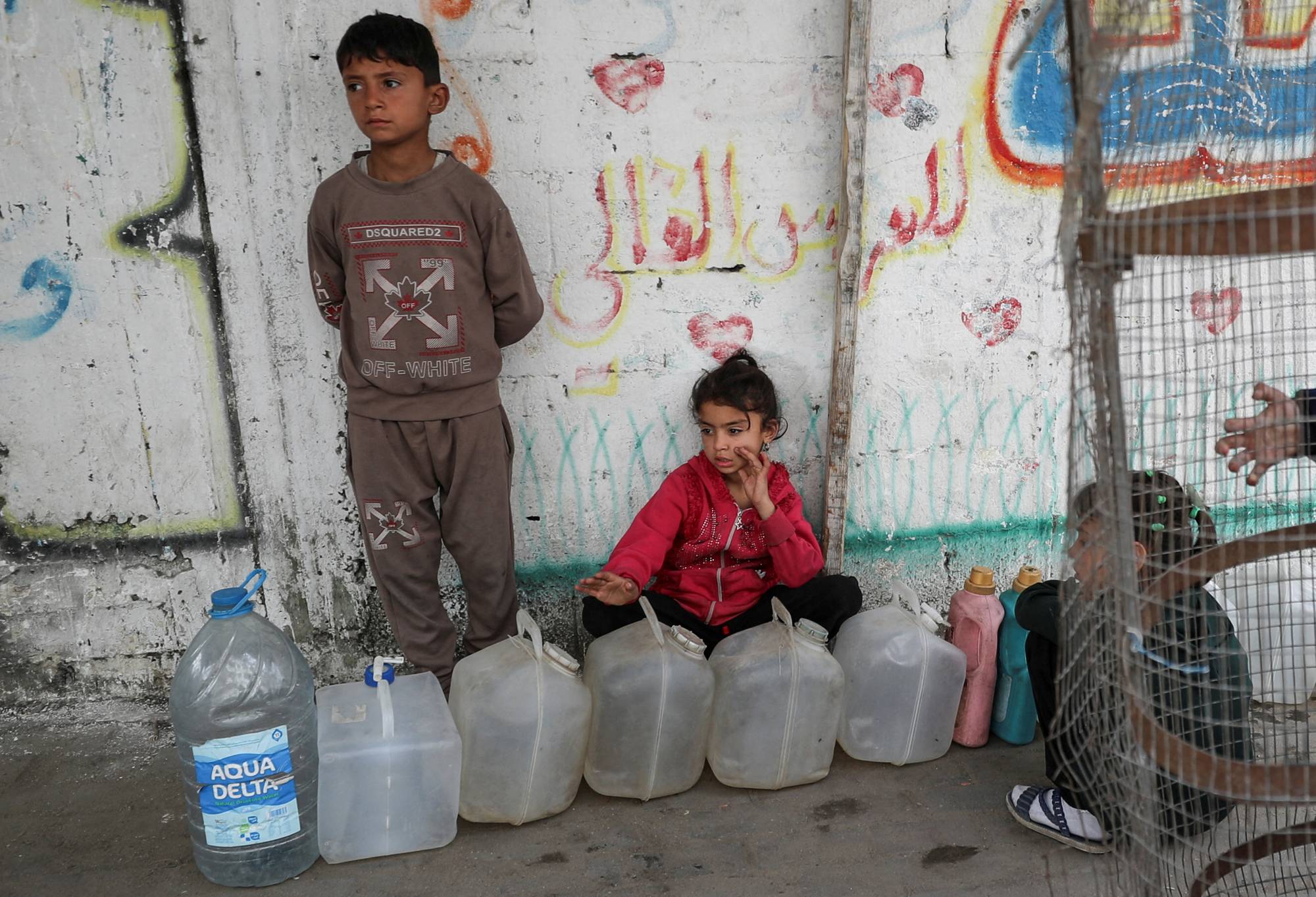 أطفال فلسطينيون يتجمعون بالقرب من غالونات المياه في مدينة غزة (رويترز)
