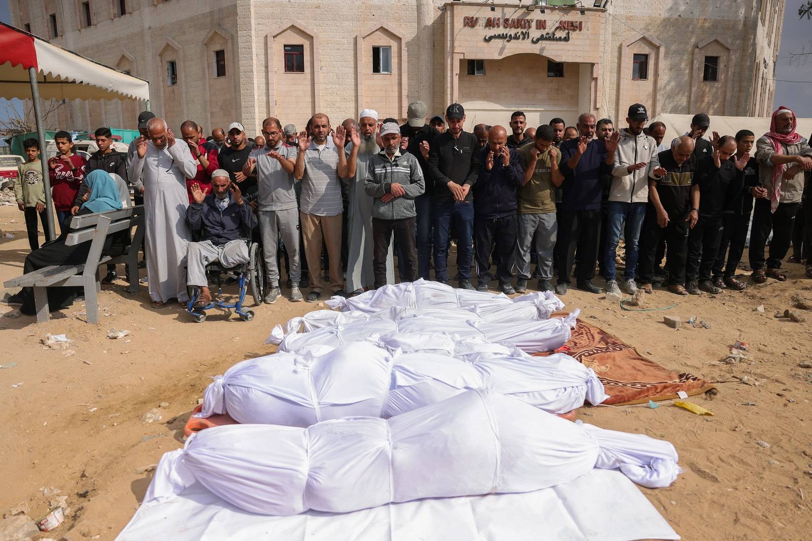 فلسطينيون يصلّون بجانب جثامين قتلوا في غارات إسرائيلية ببيت لاهيا شمال غزة (أ.ف.ب)