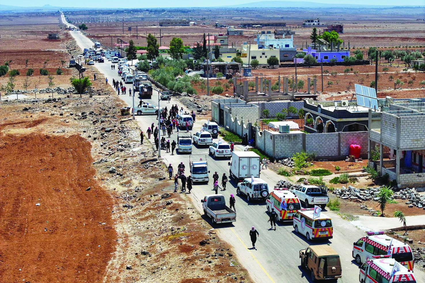 قافلة تابعة للهلال الأحمر السوري تحمل مساعدات إنسانية تعبر مدينة بصرى الشام متجهةً إلى مدينة السويداء (أ.ف.ب)