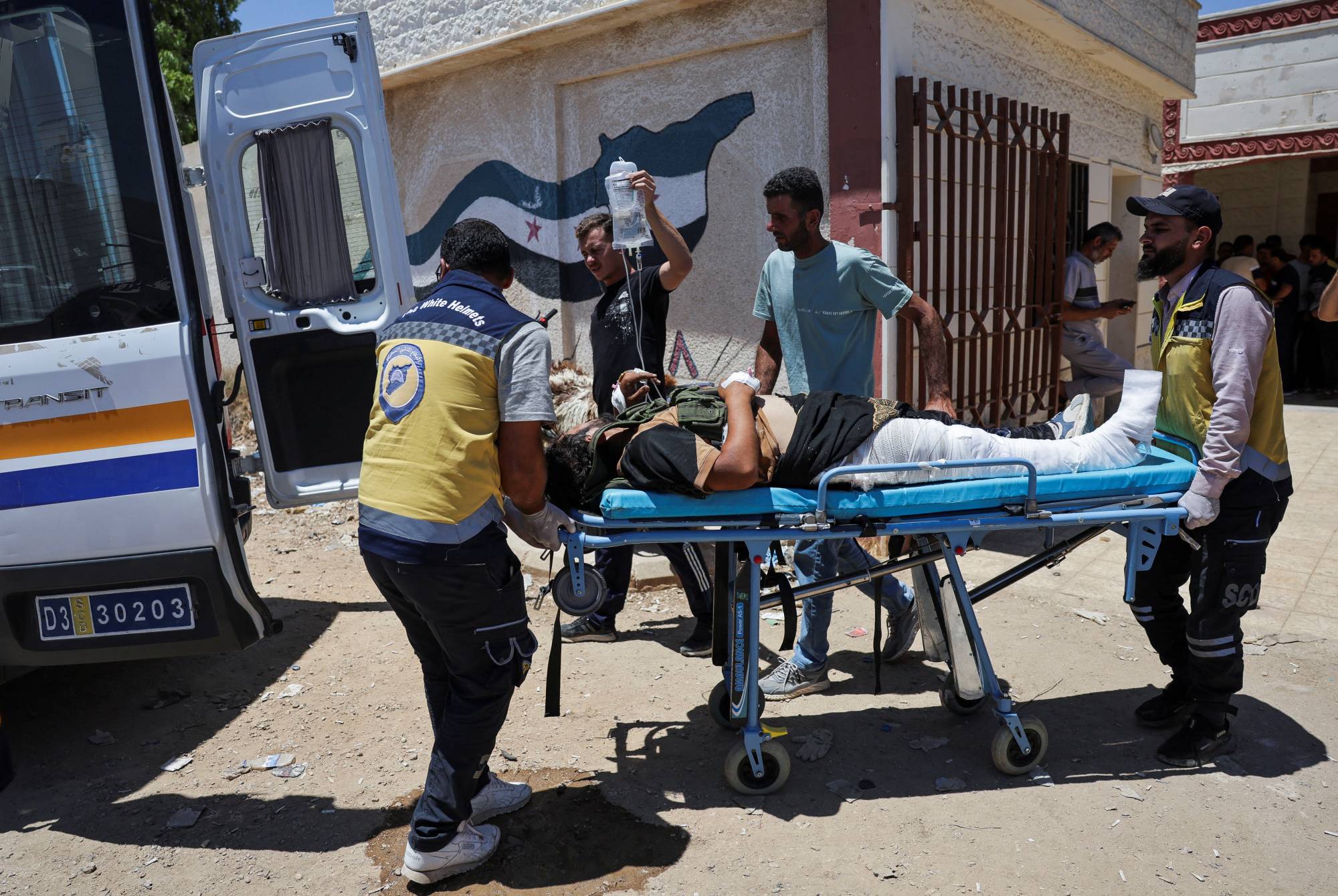مسعفون ينقلون أحد جرحى المواجهات في السويداء إلى مستشفى ميداني في درعا الجمعة (رويترز)