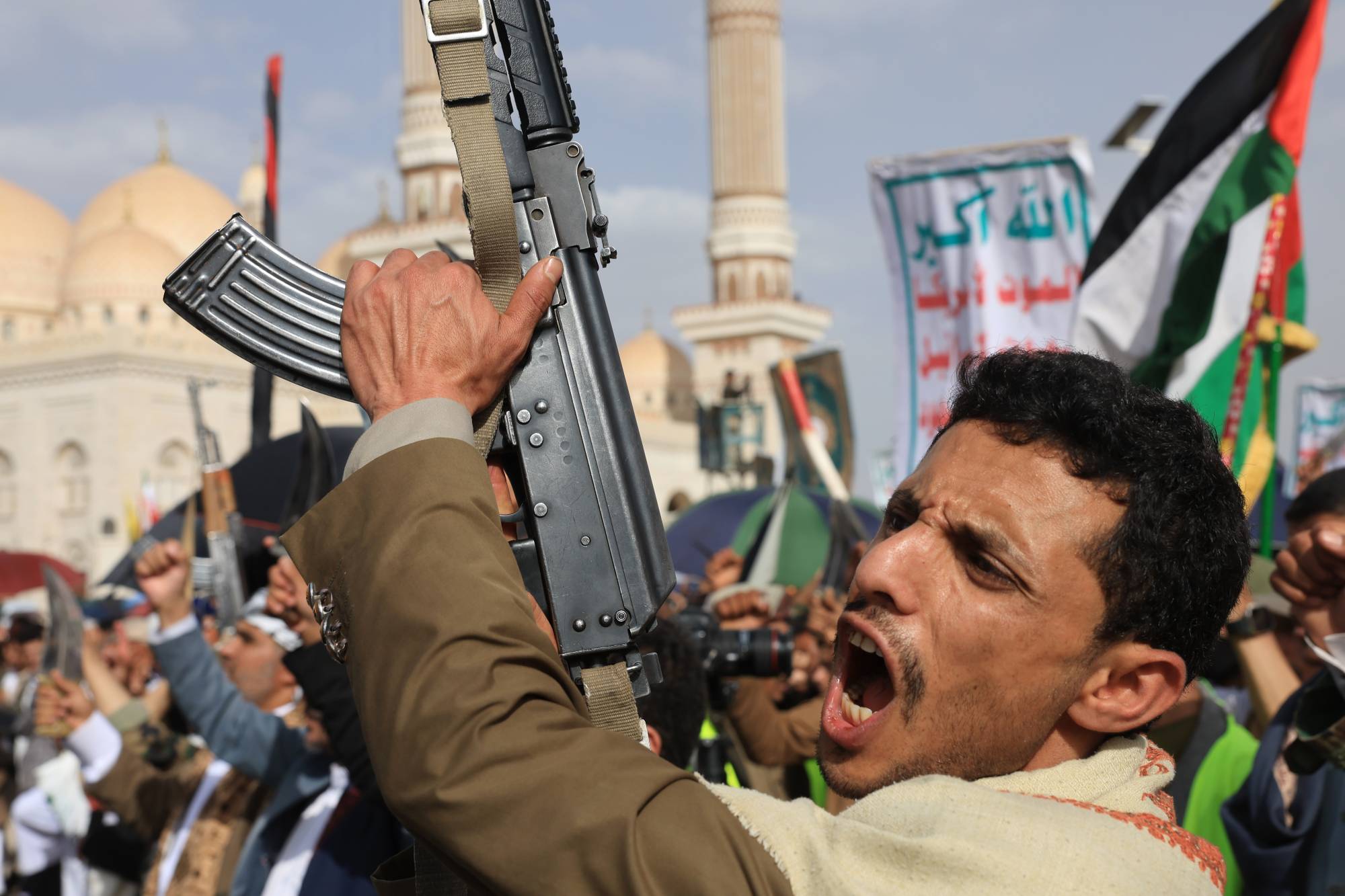 عنصر حوثي يرفع سلاحاً آلياً خلال حشد للجماعة في صنعاء (إ.ب.أ)