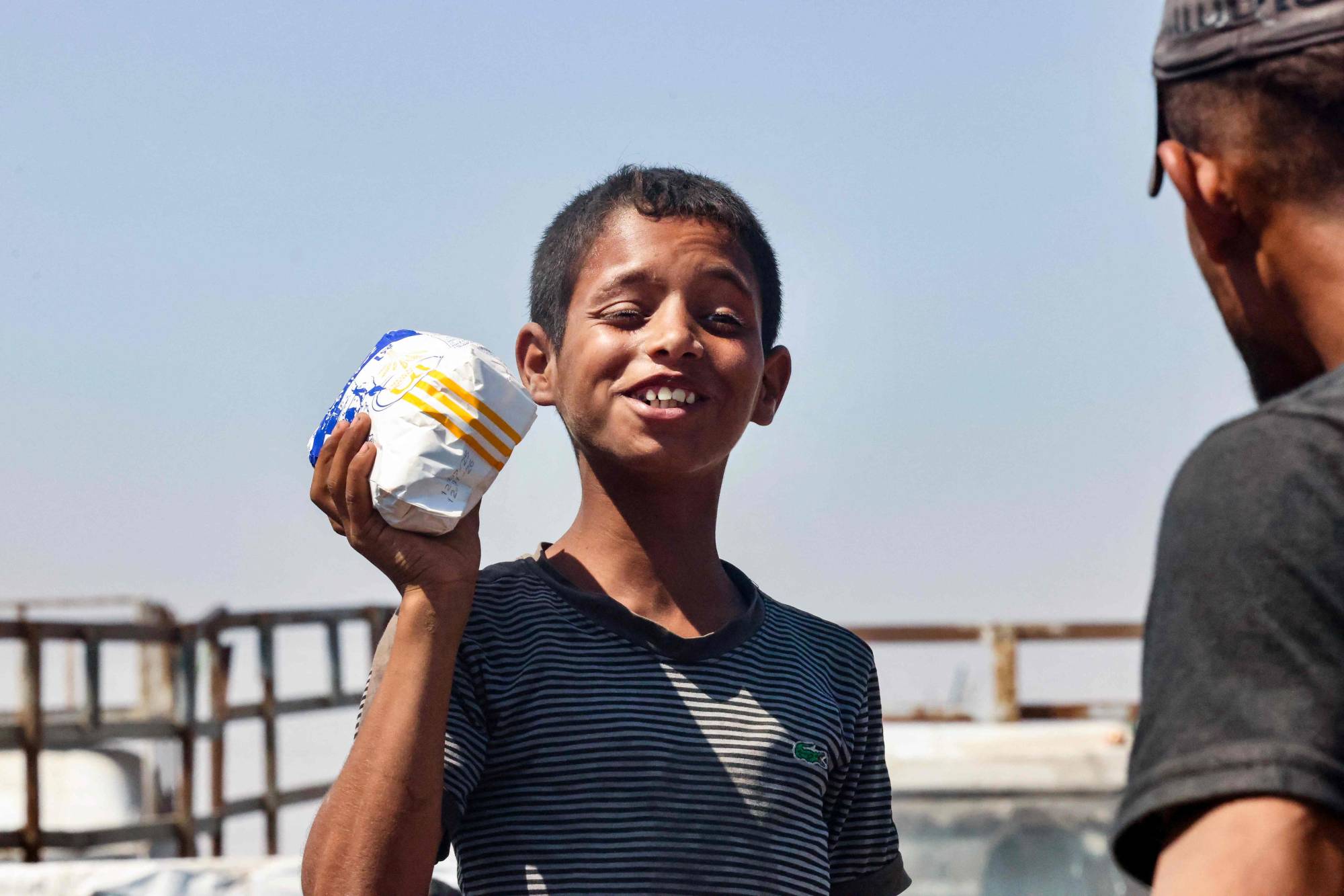 طفل فلسطيني يحمل كيساً من الطحين في مواصي رفح جنوب قطاع غزة (أ.ف.ب)