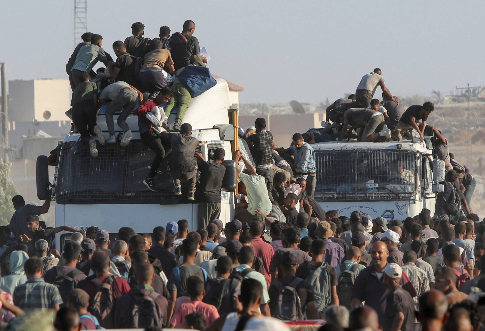 فلسطينيون يصعدون على الشاحنات بحثًا عن إمدادات غذائية في خان يونس بجنوب قطاع غزة (رويترز)