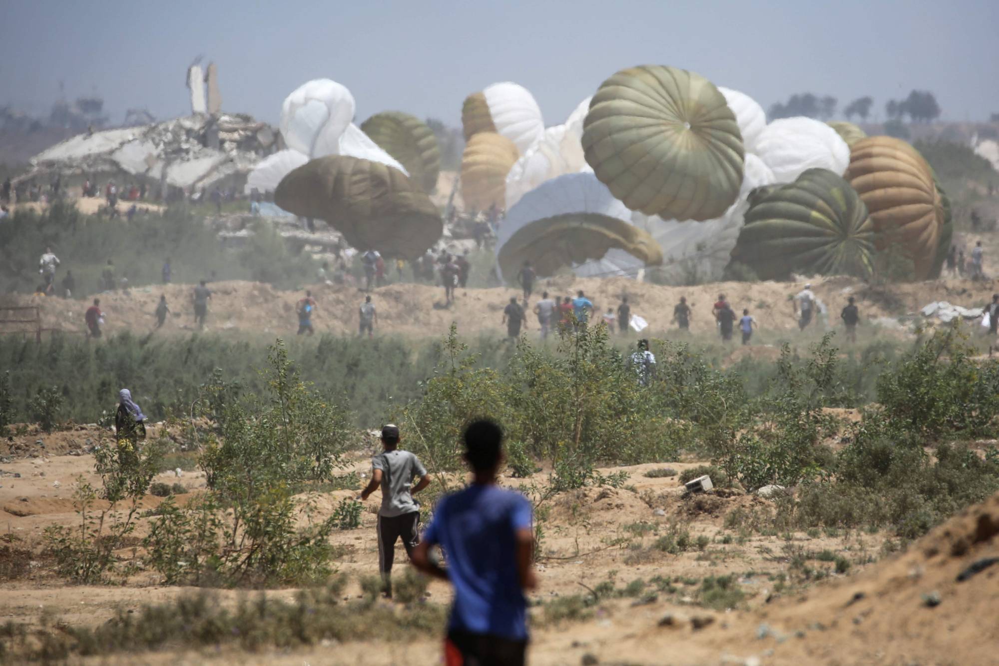 فلسطينيون يهرعون إلى موقع إسقاط مساعدات جواً في النصيرات وسط قطاع غزة يوم الأربعاء (أ.ف.ب)