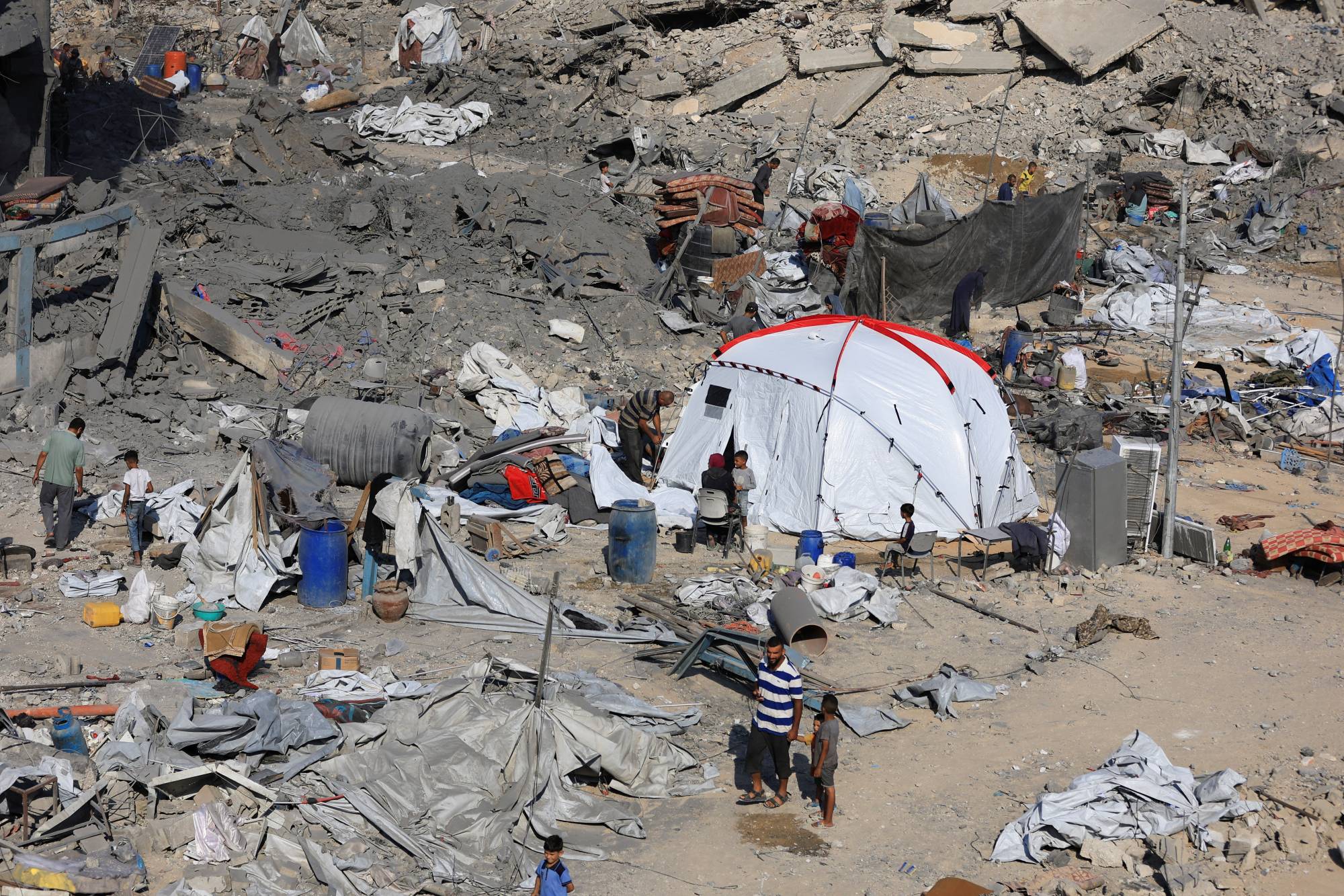 فلسطينيون ينظرون إلى الدمار في محيط مركز طبي تابع لـ«أونروا» يؤوي نازحين بعد هجوم إسرائيلي يوم الأربعاء (رويترز)