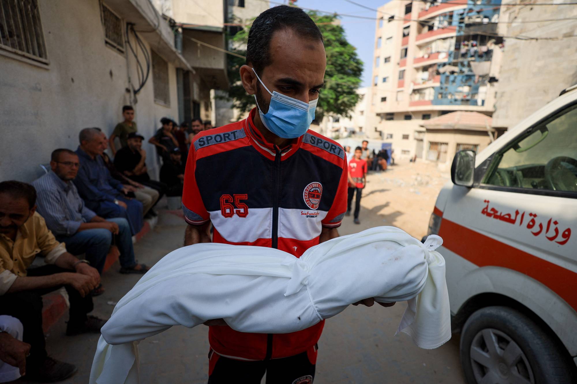 فلسطيني يحمل جثمان طفلة قُتلت في ضربة جوية أصابت بيتاً بمدينة غزة الأربعاء (رويترز)