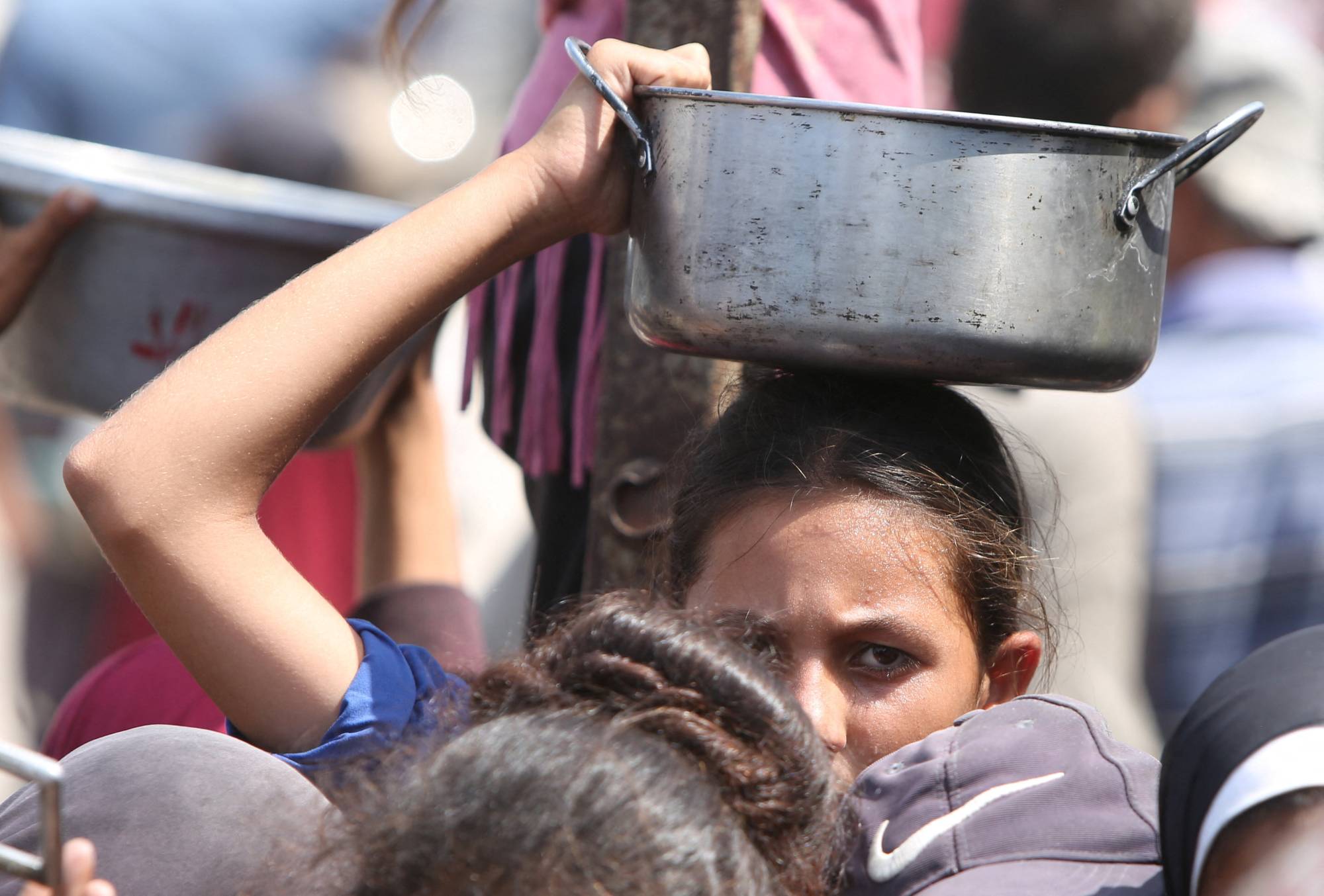 فتاة تنتظر مع كثيرين للحصول على طعام من مطبخ خيري في خان يونس بقطاع غزة الخميس (رويترز)