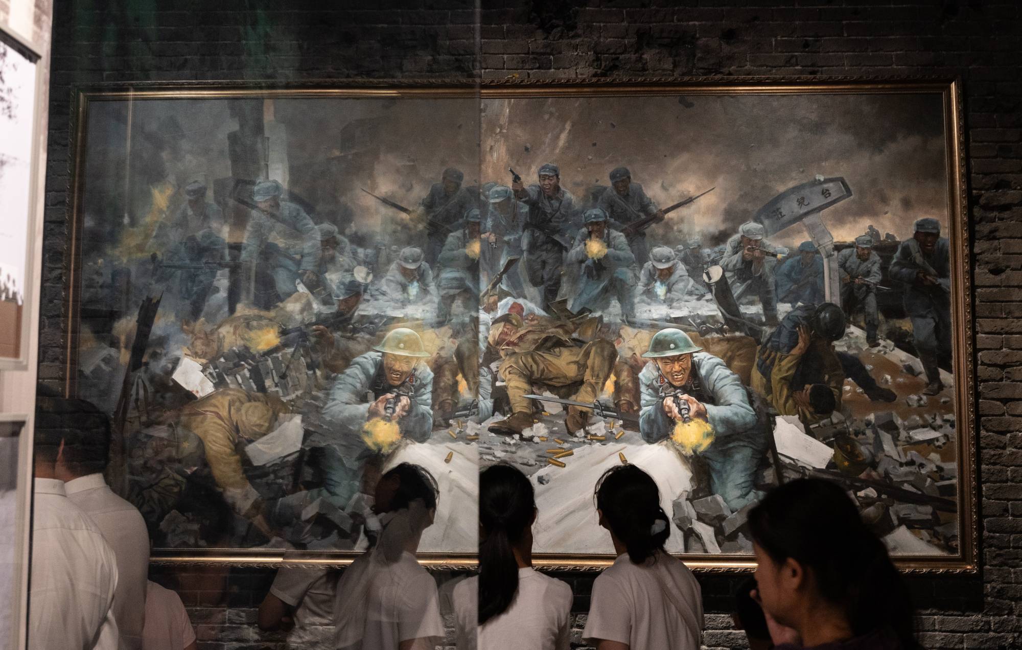 أشخاص ينظرون إلى لوحة في متحف حرب المقاومة الشعبية الصينية ضد العدوان الياباني في بكين (إ.ب.أ)