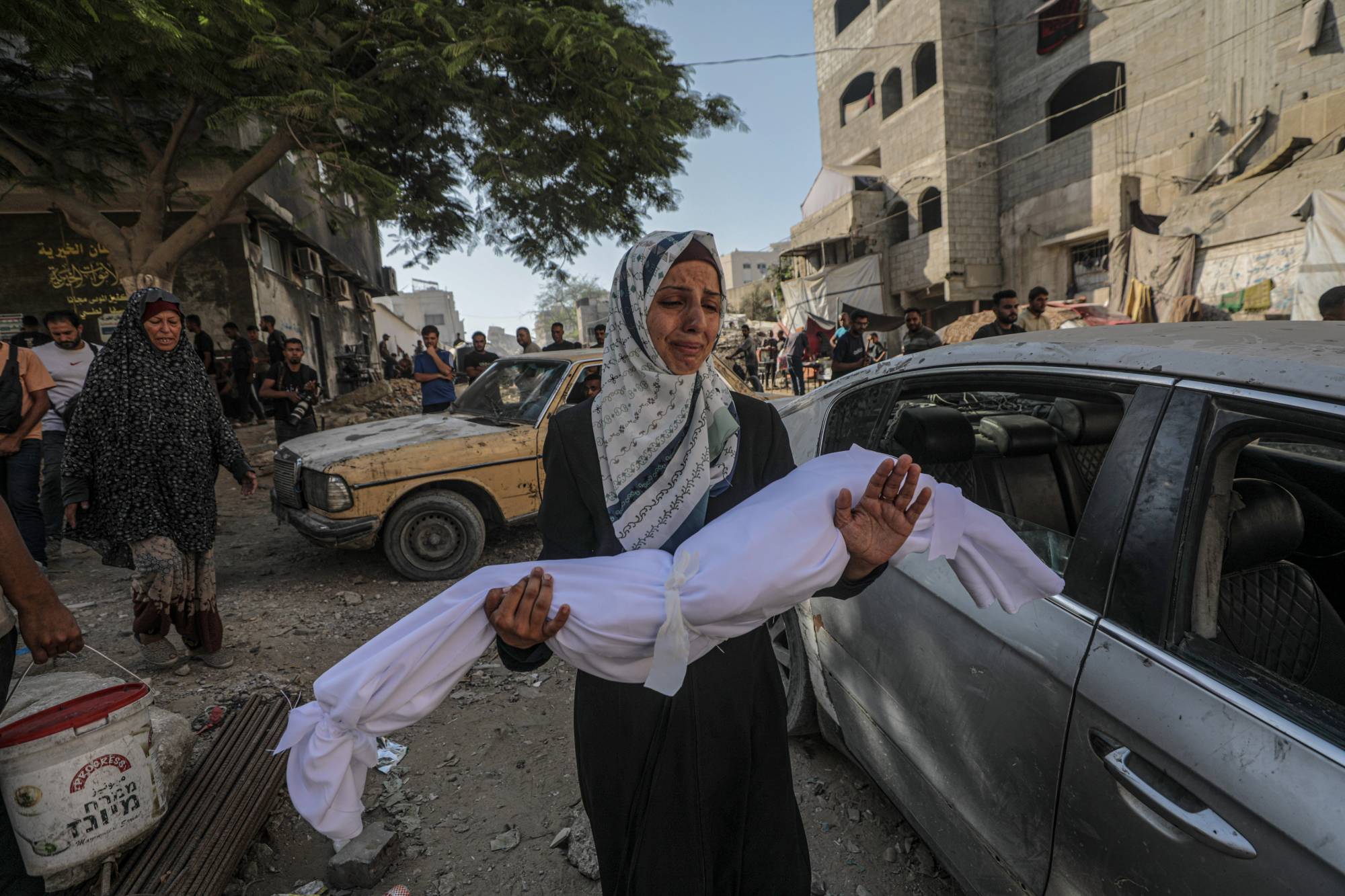 فلسطينية تحمل جثمان طفلها قرب «مستشفى الشفاء» بمدينة غزة الجمعة (إ.ب.أ)