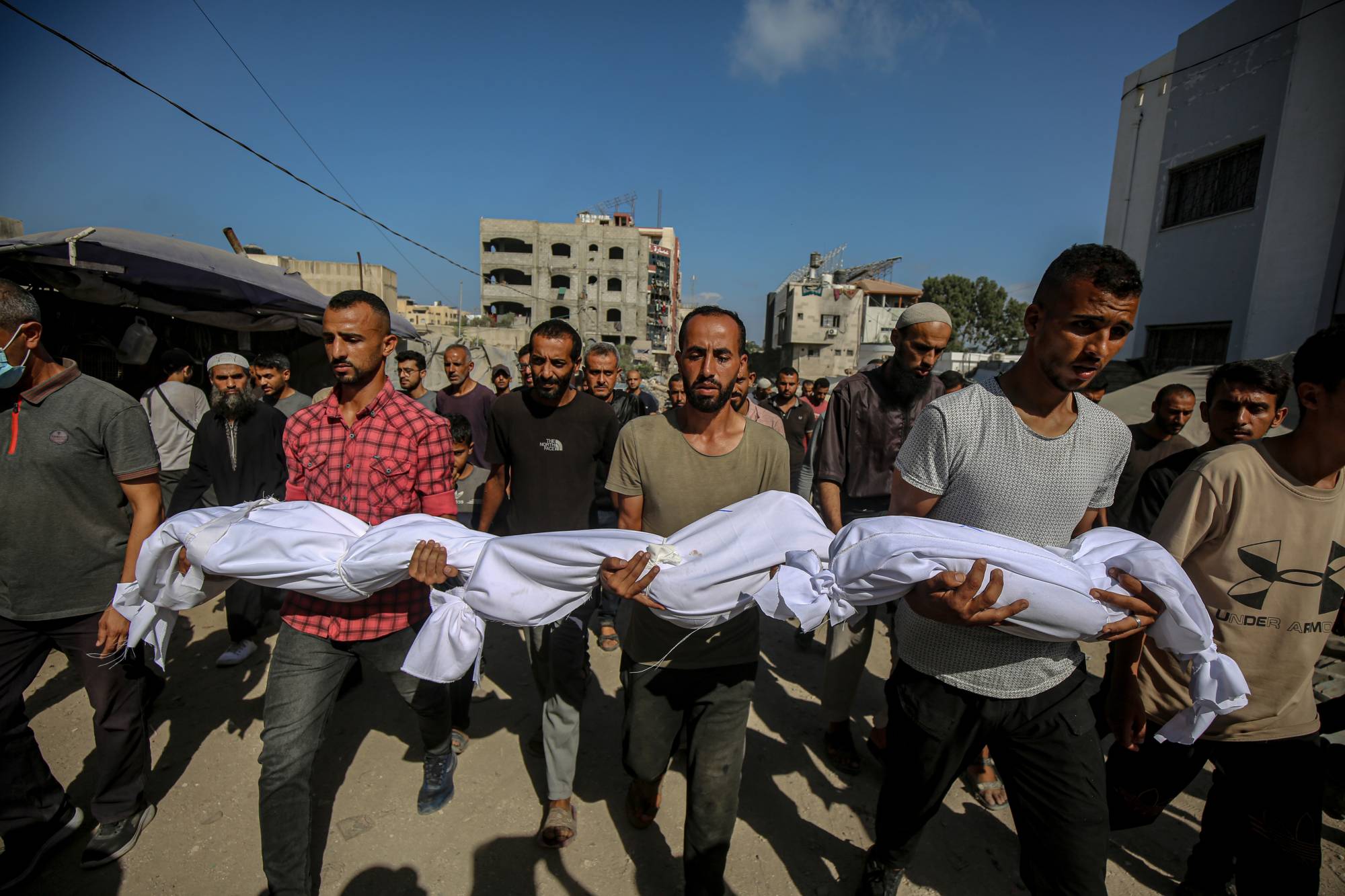 فلسطينيون يحملون جثامين ذويهم بعد ضربات إسرائيلية في مدينة غزة فجر الثلاثاء (د.ب.أ)