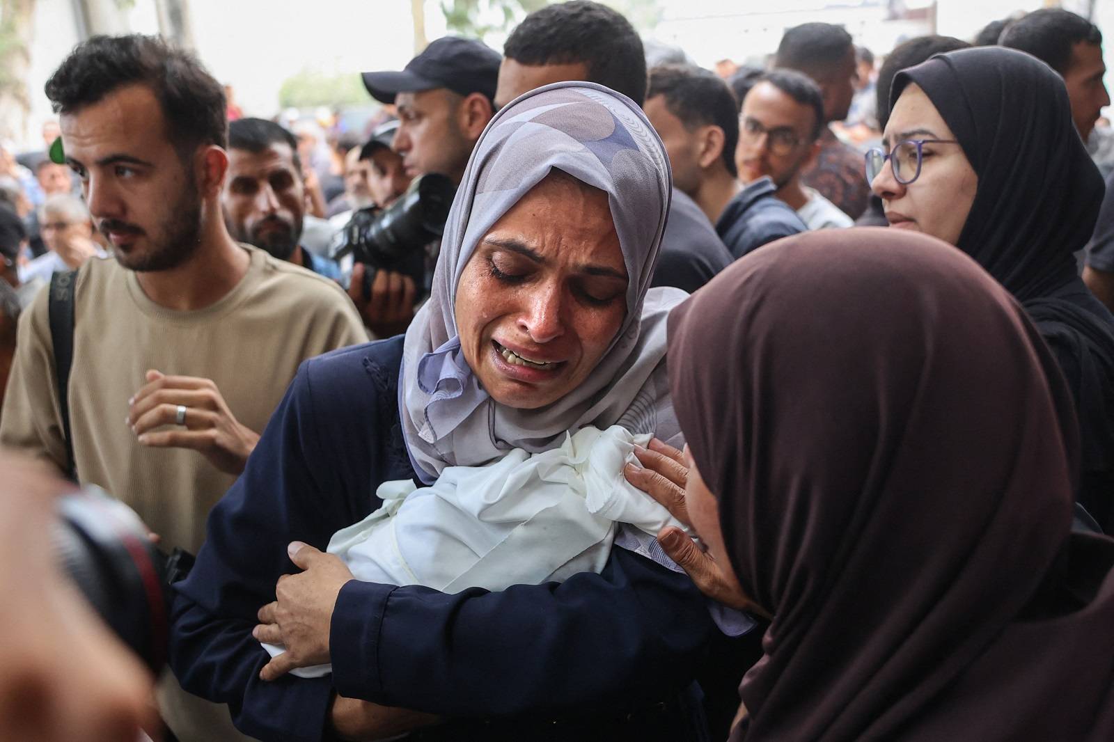 امرأة فلسطينية تبكي وهي تحمل جثمان رضيع قُتل في غارات إسرائيلية على مدينة غزة (أ.ف.ب)