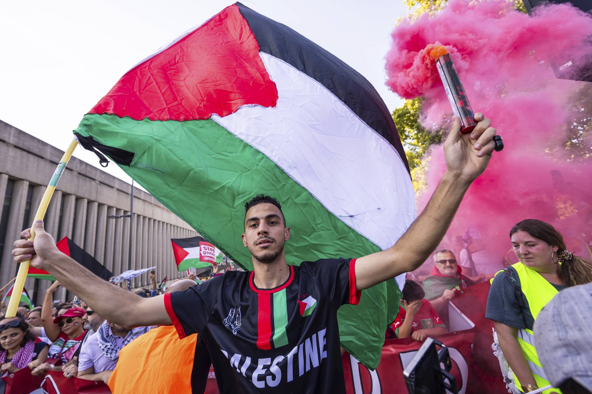 رجل يحمل مشعلاً ويلوح بالعلم الفلسطيني أثناء مشاركته في المظاهرة الداعمة للفلسطينيين في بروكسل اليوم (أ.ب)