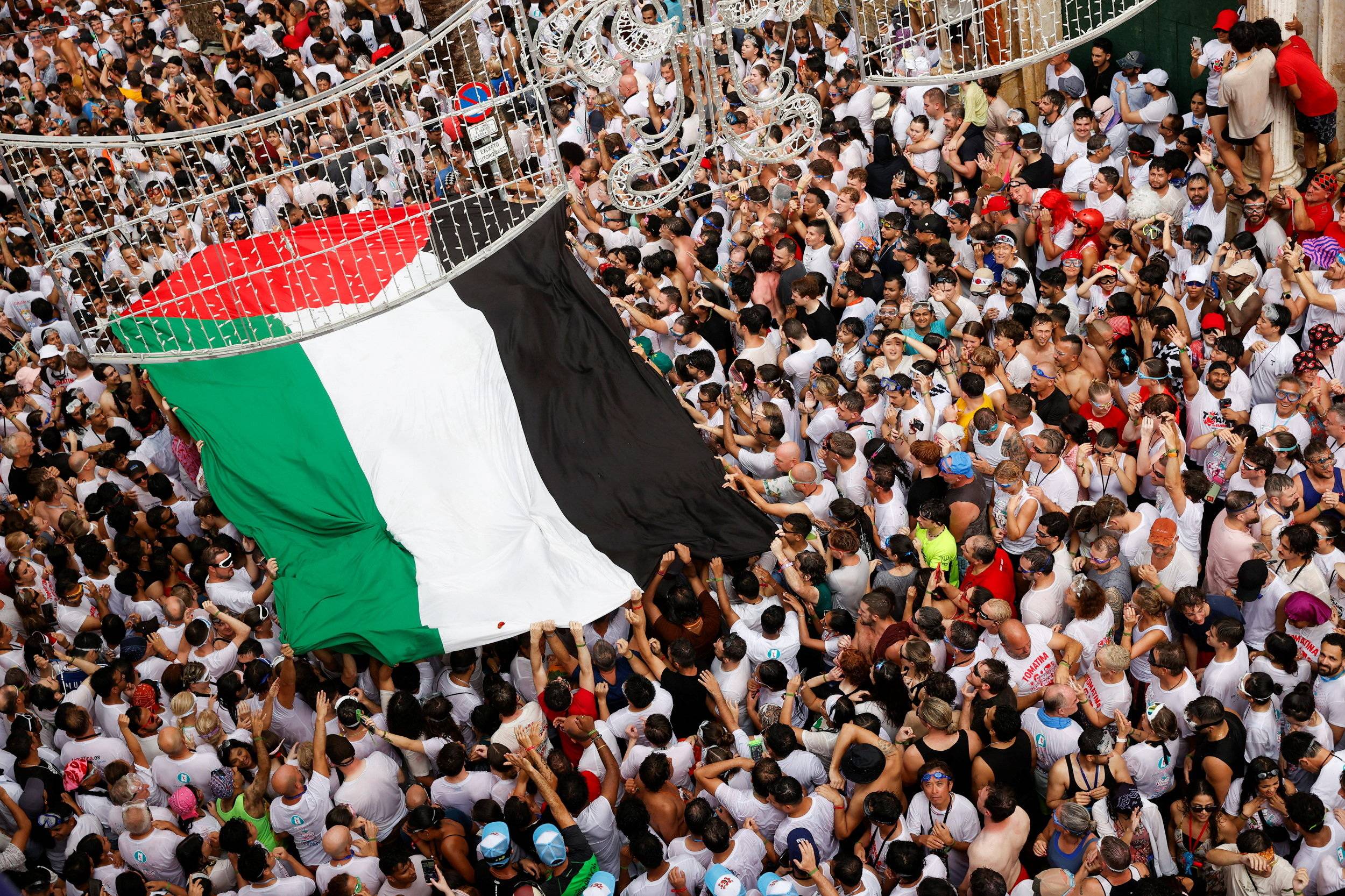 مشاركون يحملون علماً فلسطينياً كبيراً خلال مهرجان الطماطم السنوي في بونول بالقرب من فالنسيا (رويترز)