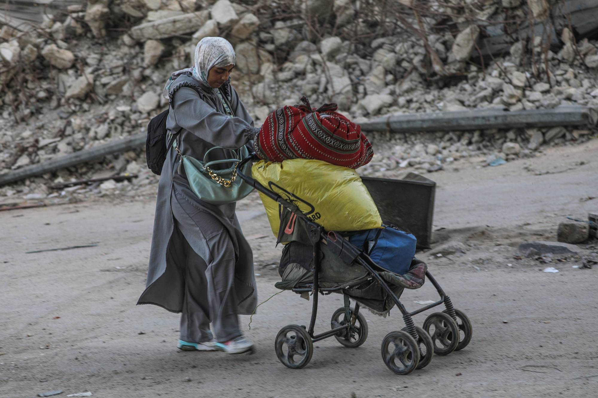 امرأة فلسطينية نازحة داخلياً تفر من منطقة استهدفتها غارة جوية إسرائيلية في مدينة غزة (إ.ب.أ)