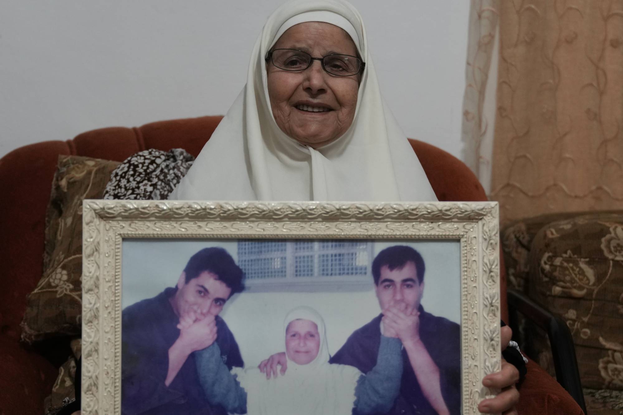 حليمة شماسنة حاملة صورة لابنيها (أ.ب)