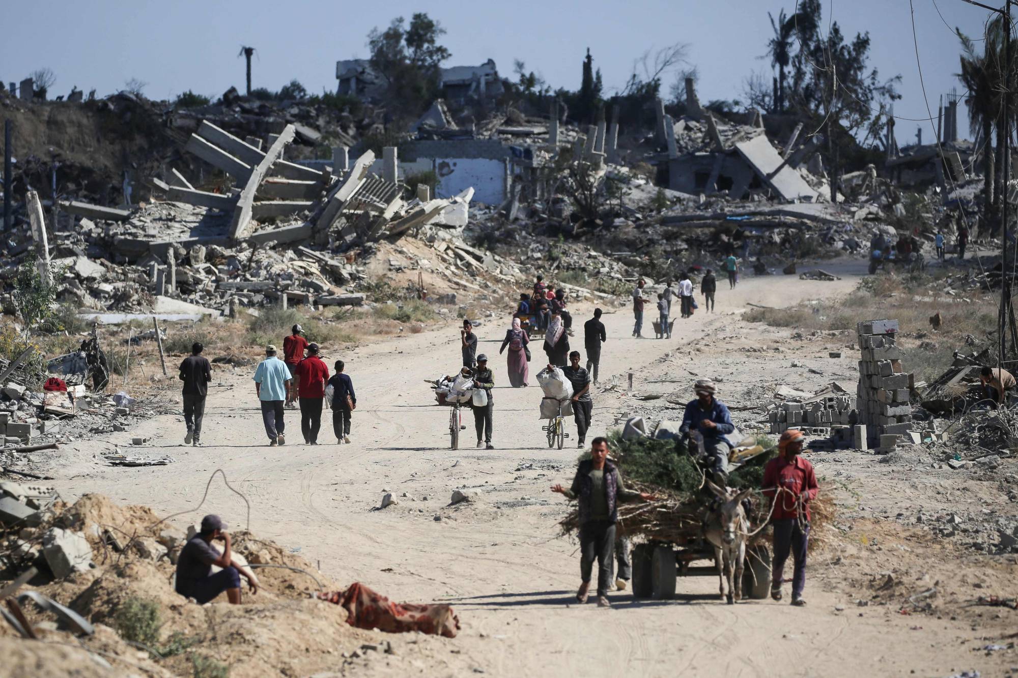 فلسطينيون نازحون يسيرون أمام المباني المدمرة أثناء عودتهم إلى منازلهم في منطقة الزهراء شمال مخيم النصيرات للاجئين في وسط قطاع غزة 14 أكتوبر 2025 بعد يوم من دخول وقف إطلاق النار حيّز التنفيذ (أ.ف.ب)