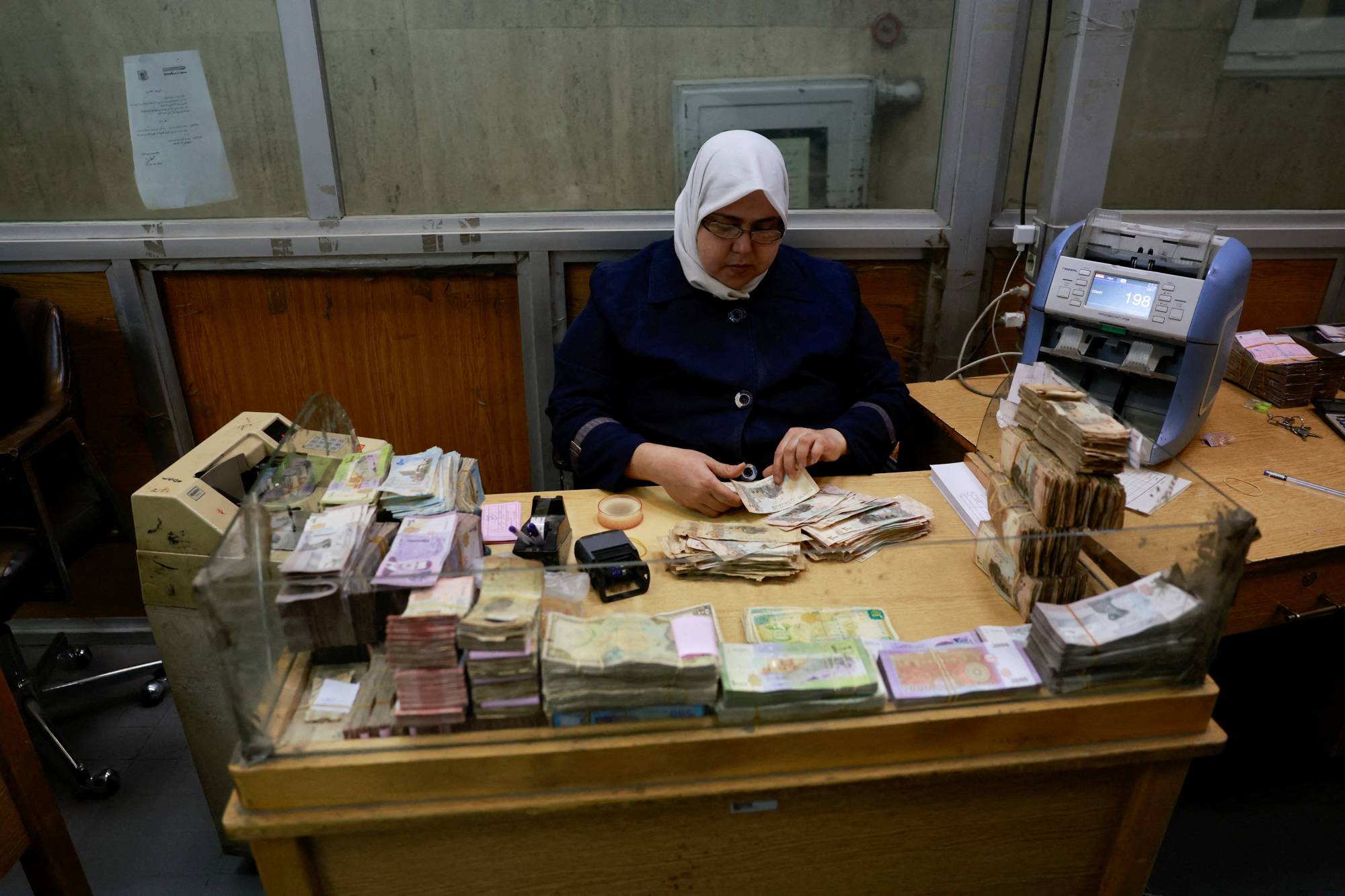 موظفة تعدّ النقود في البنك المركزي السوري بعد الإطاحة بالرئيس بشار الأسد (أرشيفية - رويترز)