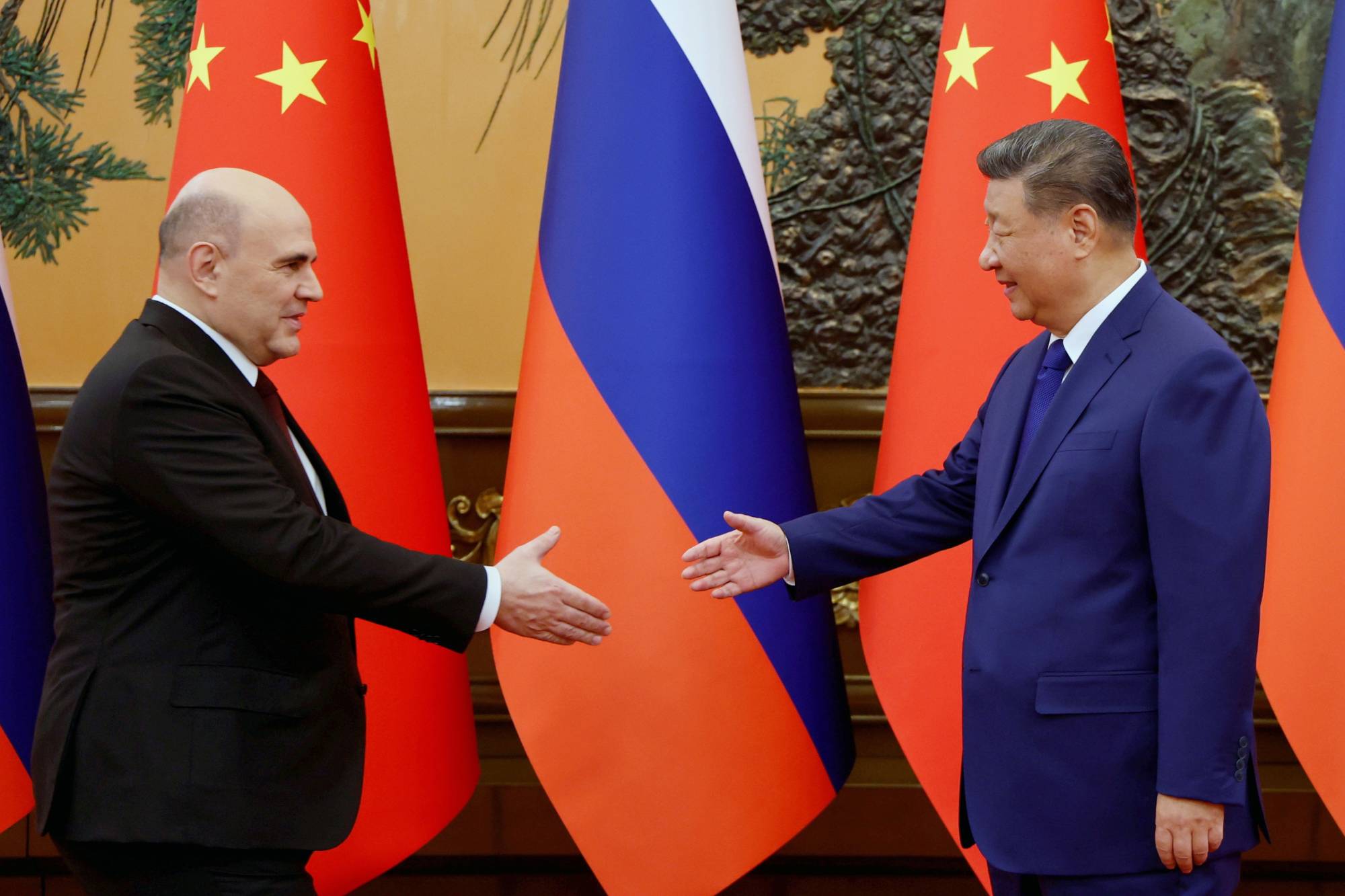 الرئيس الصيني شي جينبينغ ورئيس الوزراء الروسي ميخائيل ميشوستين يتصافحان قبل محادثاتهما في مجلس الشعب ببكين (أ.ب)