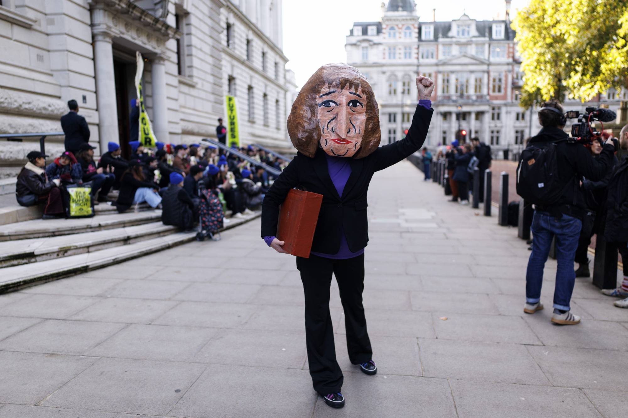 متظاهرة من مجموعة «صعود الصفقة الخضراء الجديدة» ترتدي قناعاً يُصوّر وزيرة الخزانة البريطانية (إ.ب.أ)