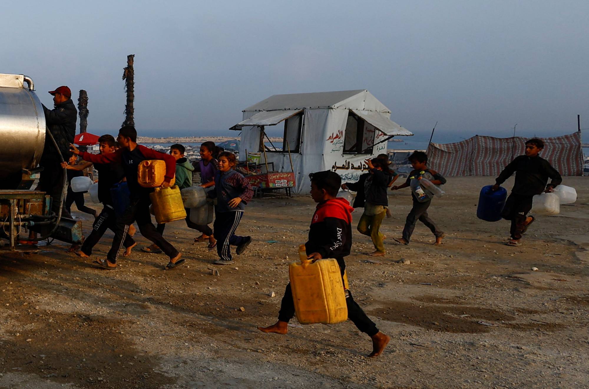 فلسطينيون يحملون عبوات للحصول على ماء في غزة (رويترز)