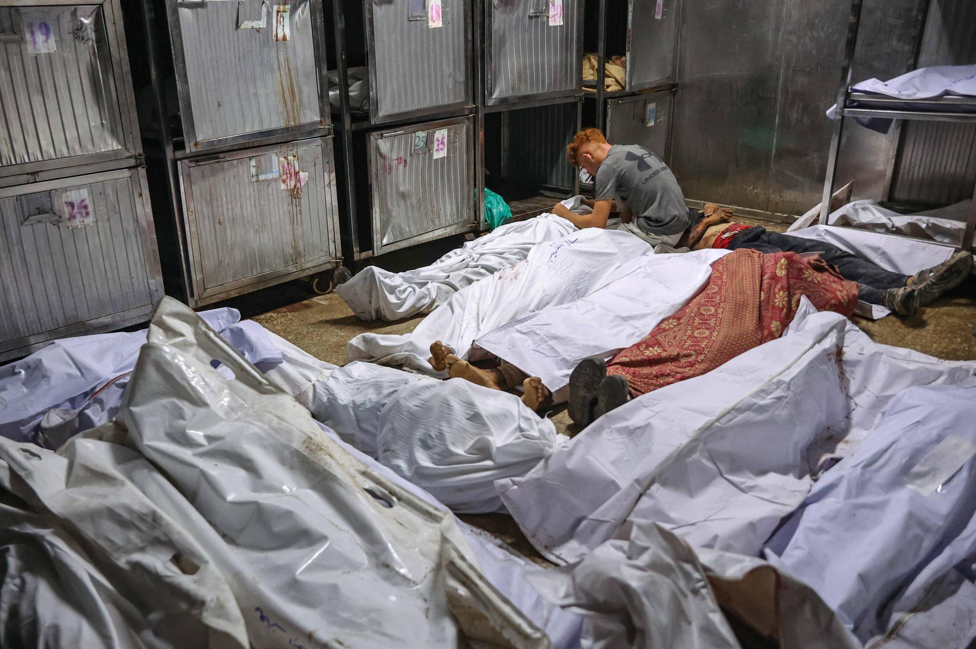 فلسطيني يجلس وسط الجثث في مشرحة مستشفى «الشفاء» غرب بيت لاهيا شمال قطاع غزة (أ.ف.ب)