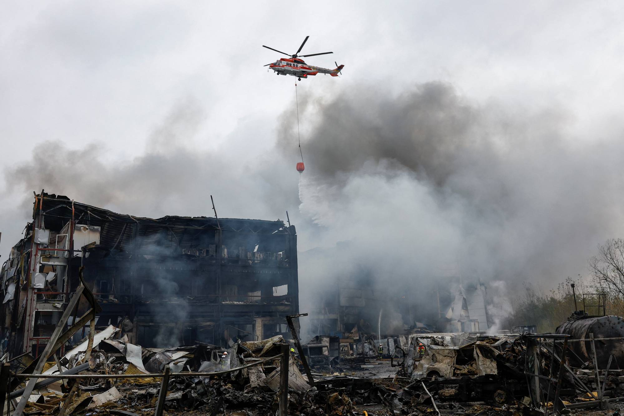 هليكوبتر تسقط المياه على مستودعات الأغذية التي تعرضت لقصف صاروخي روسي في كييف (رويترز)
