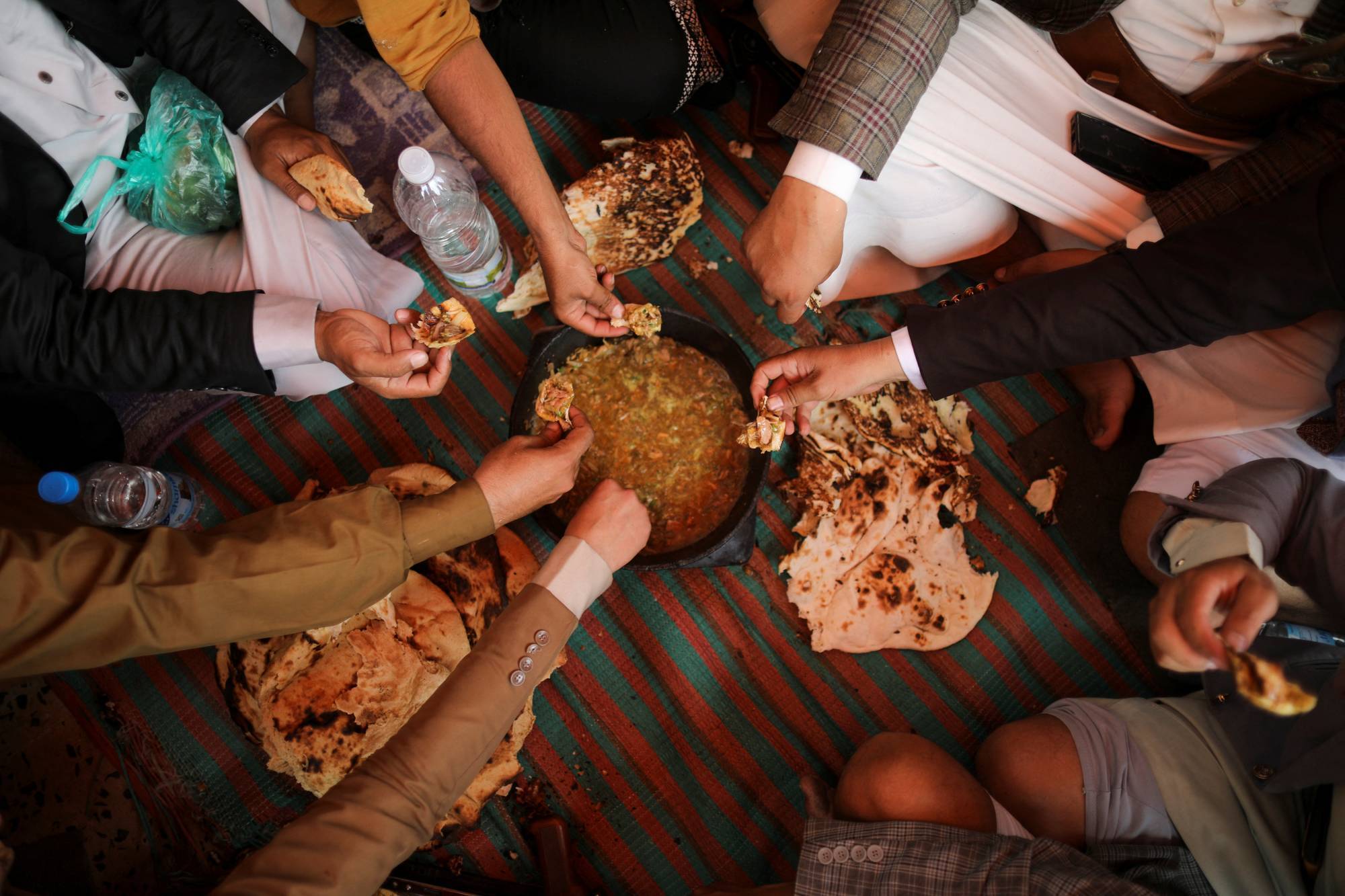 يمنيون في صنعاء يتناولون وجبة «السلتة» الشعبية بأحد المطاعم (رويترز)