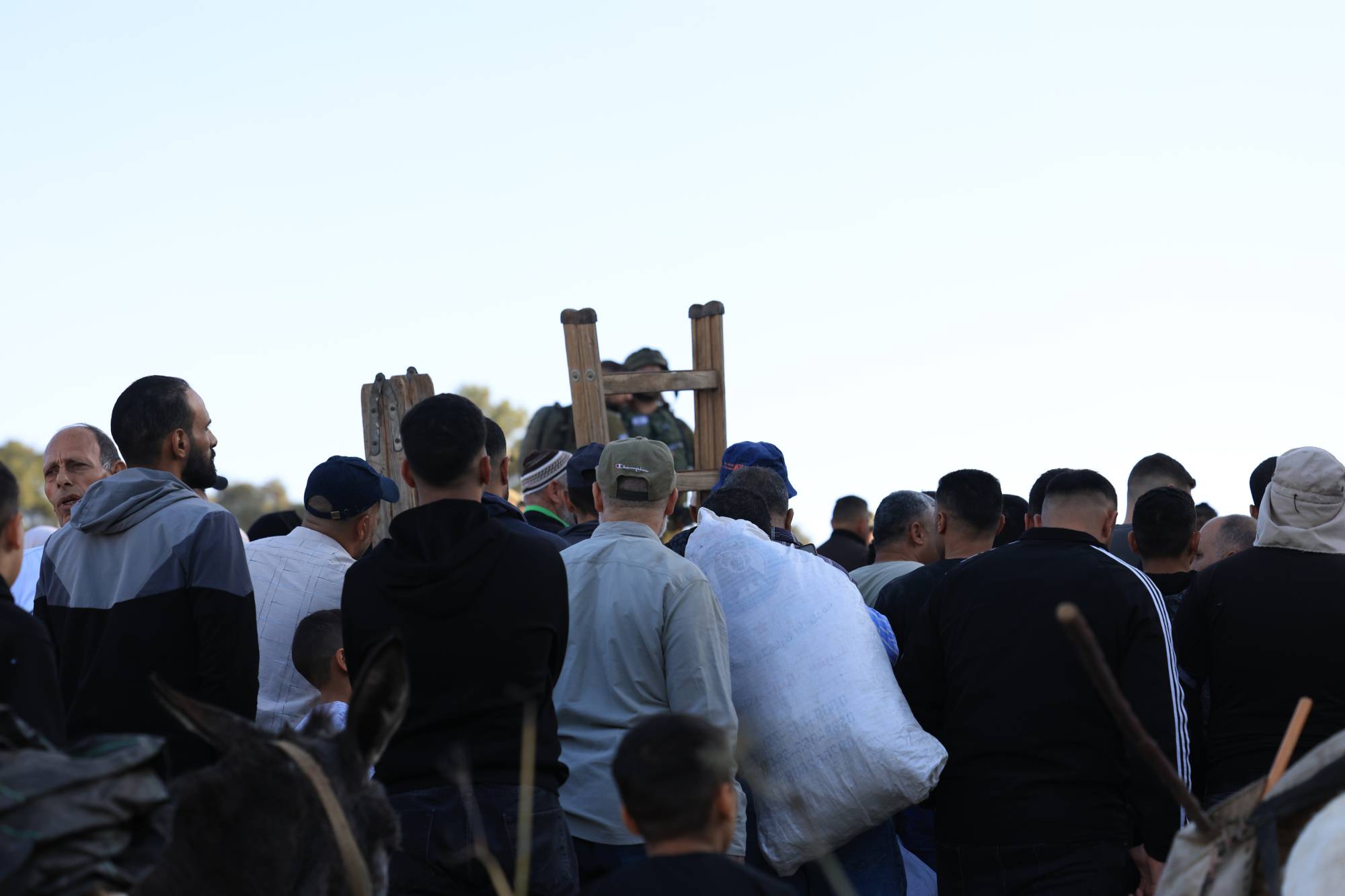 جنود إسرائيليون يسمحون لفلسطينيين المرور عبر بوابة تتيح لهم الوصول إلى حقول زيتون قرب مستوطنة ألون موريه بالقرب من مدينة نابلس بالضفة الغربية السبت (إ.ب.أ)