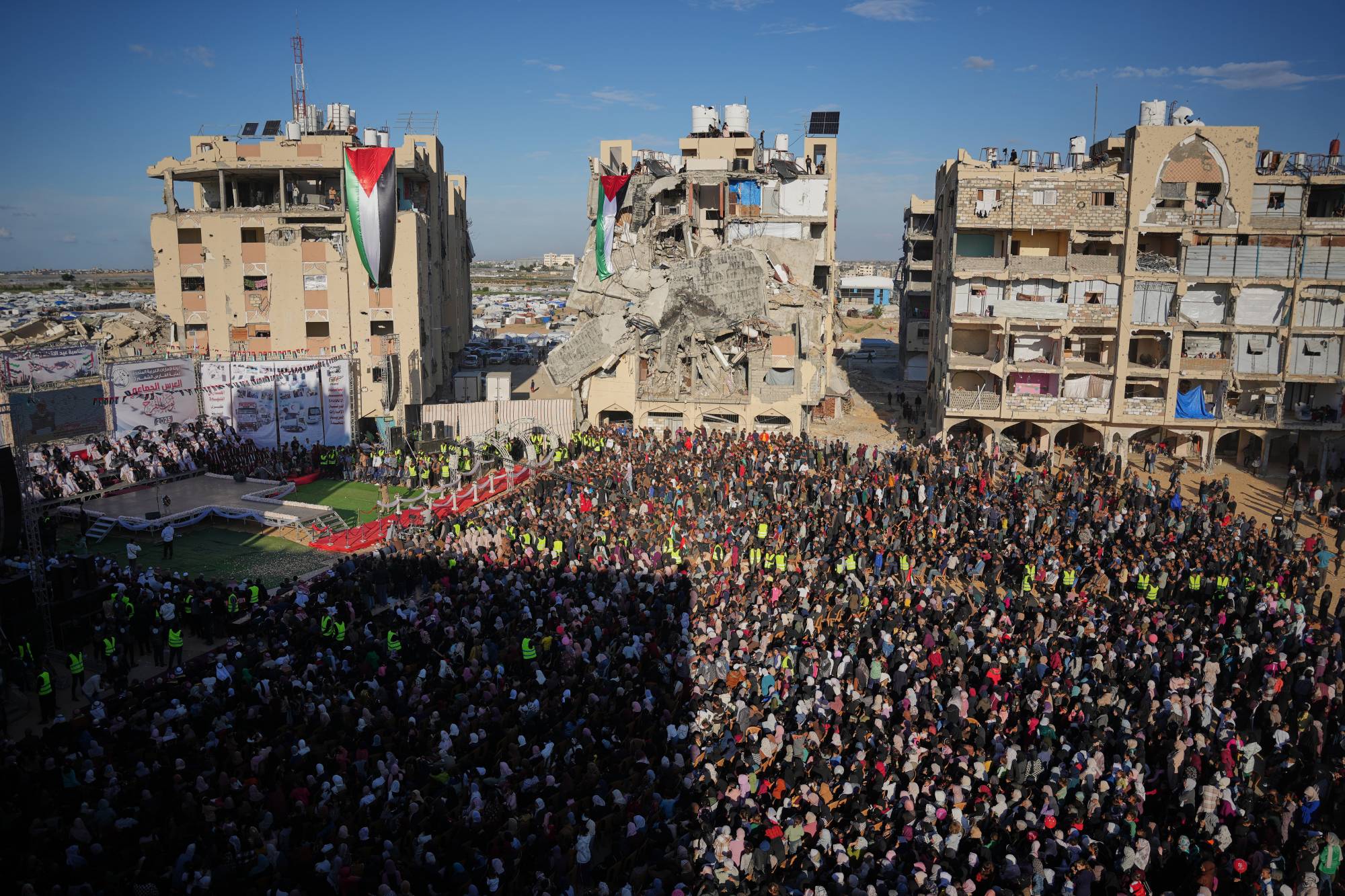 فلسطينيون يشاهدون ويحتفلون بحفل زفاف جماعي في مدينة حمد في خان يونس بقطاع غزة (أ.ب)