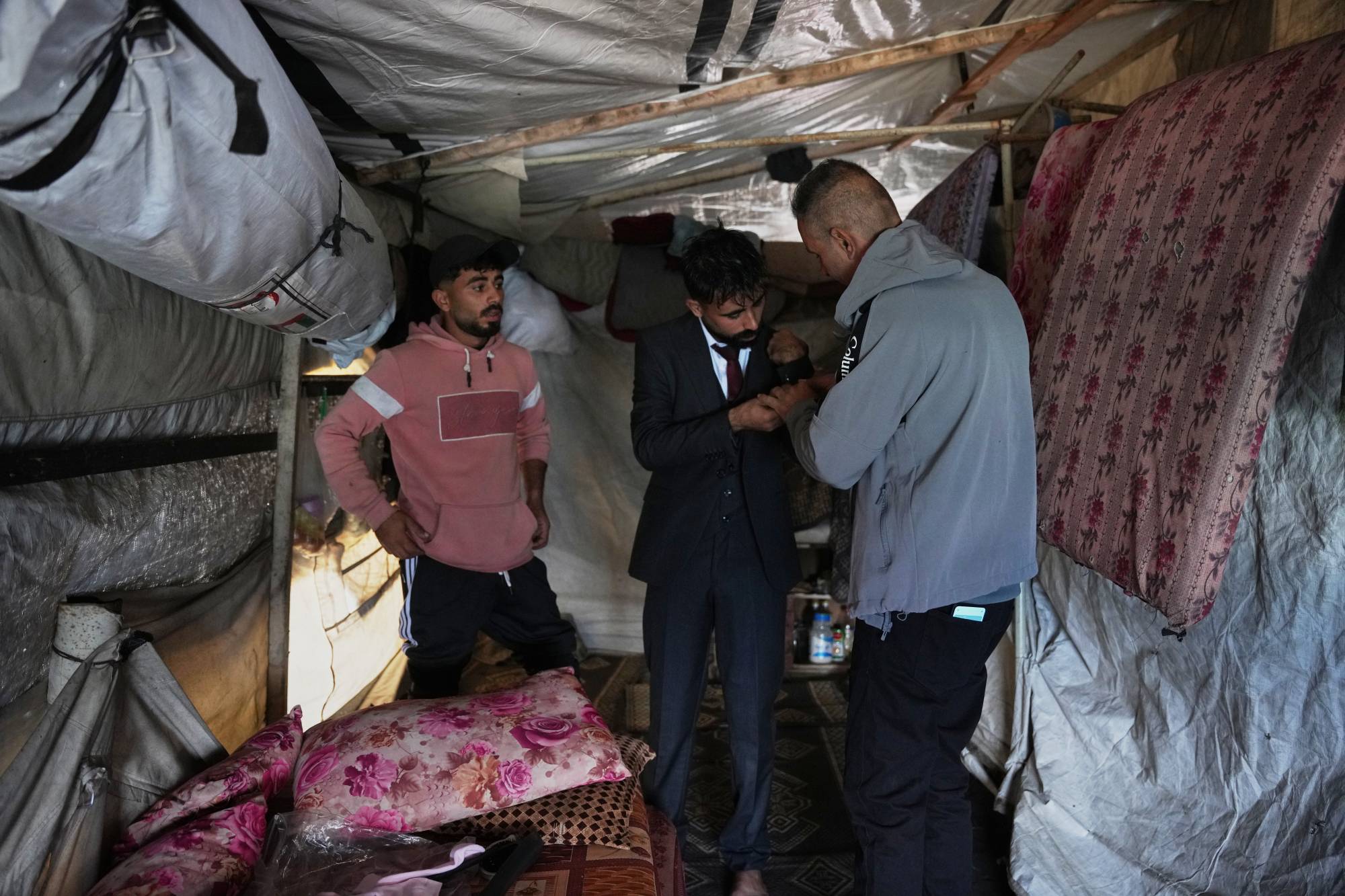 يساعد الفلسطيني أسامة لووا ابنه حكمت على ارتداء بدلة زفافه (أ.ب)