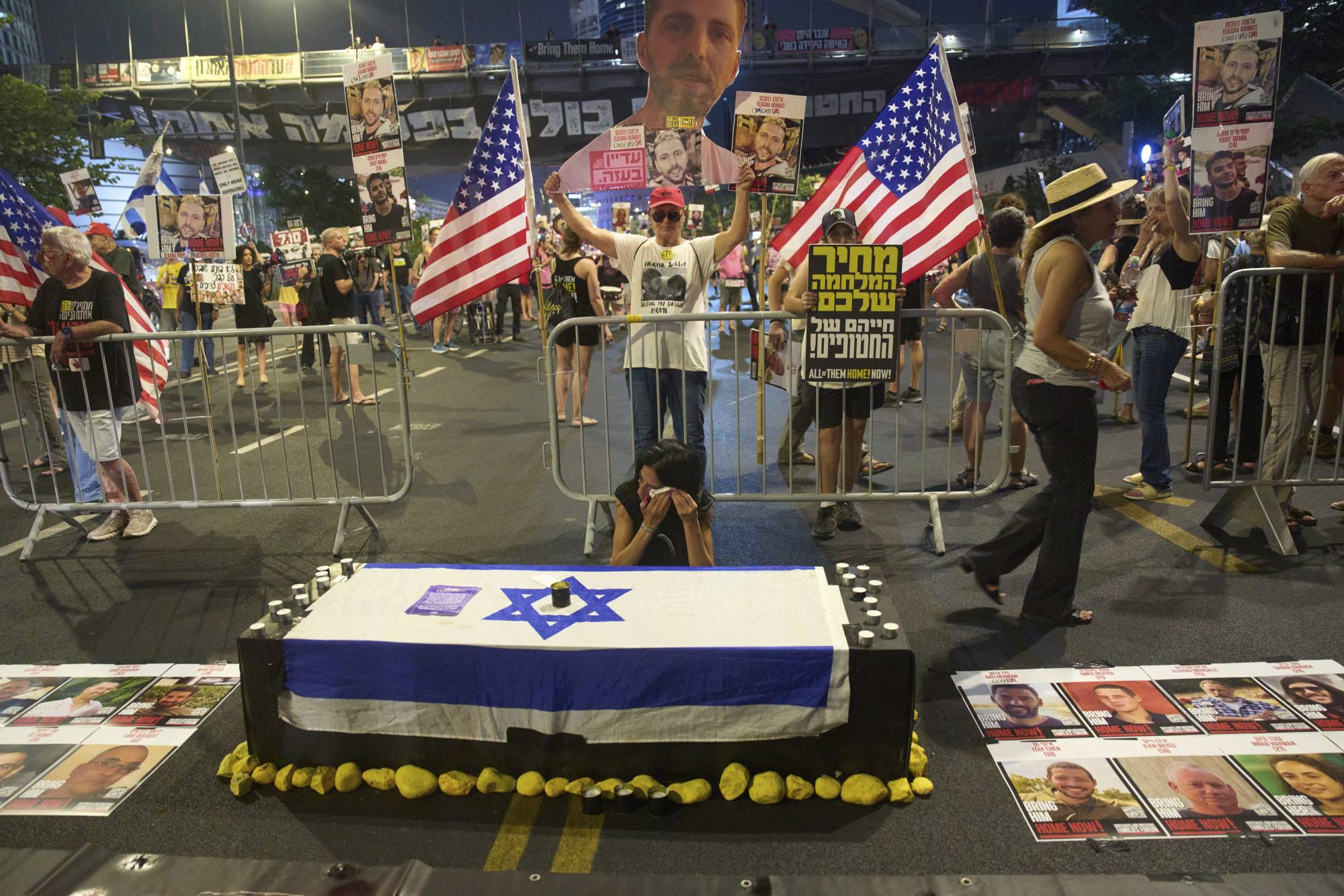 Gazze Şeridi’nde tutulan esirlerden birinin annesi, 12 Ağustos 2025'te Tel Aviv'de Gazze savaşının sona erdirilmesi ve esirlerin serbest bırakılması için düzenlenen protesto sırasında bir tabut maketinin yanında oturuyor. (AP)