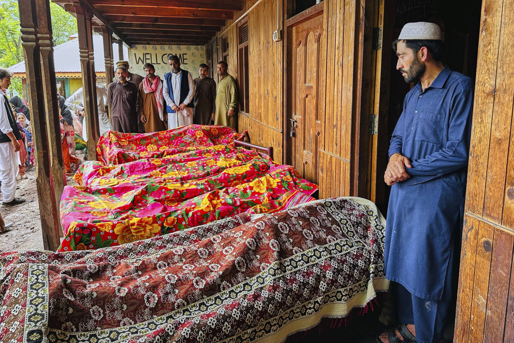  Pakistan'ın Azad Cammu Keşmir bölgesinin başkenti Muzafferabad yakınlarındaki Naryan Behak köyünde, şiddetli yağmurların yol açtığı sel felaketinde hayatını kaybedenlerin cenazelerinin yanında bekleyen vatandaşlar (AP)