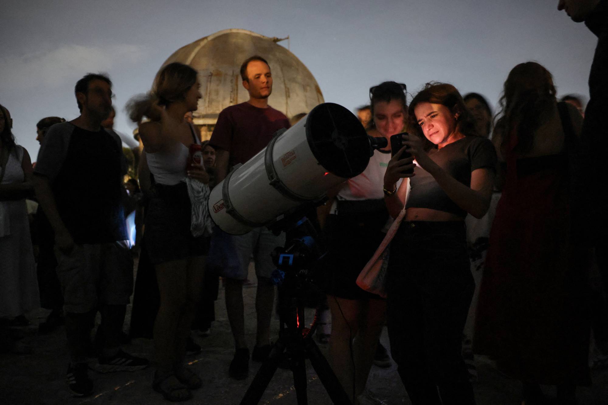  Bir kadın, Yunanistan'ın başkenti Atina'daki antik Atina Gözlemevi yakınlarında gerçekleşen tutulma sırasında teleskopla ayın fotoğrafını çekiyor (Reuters)