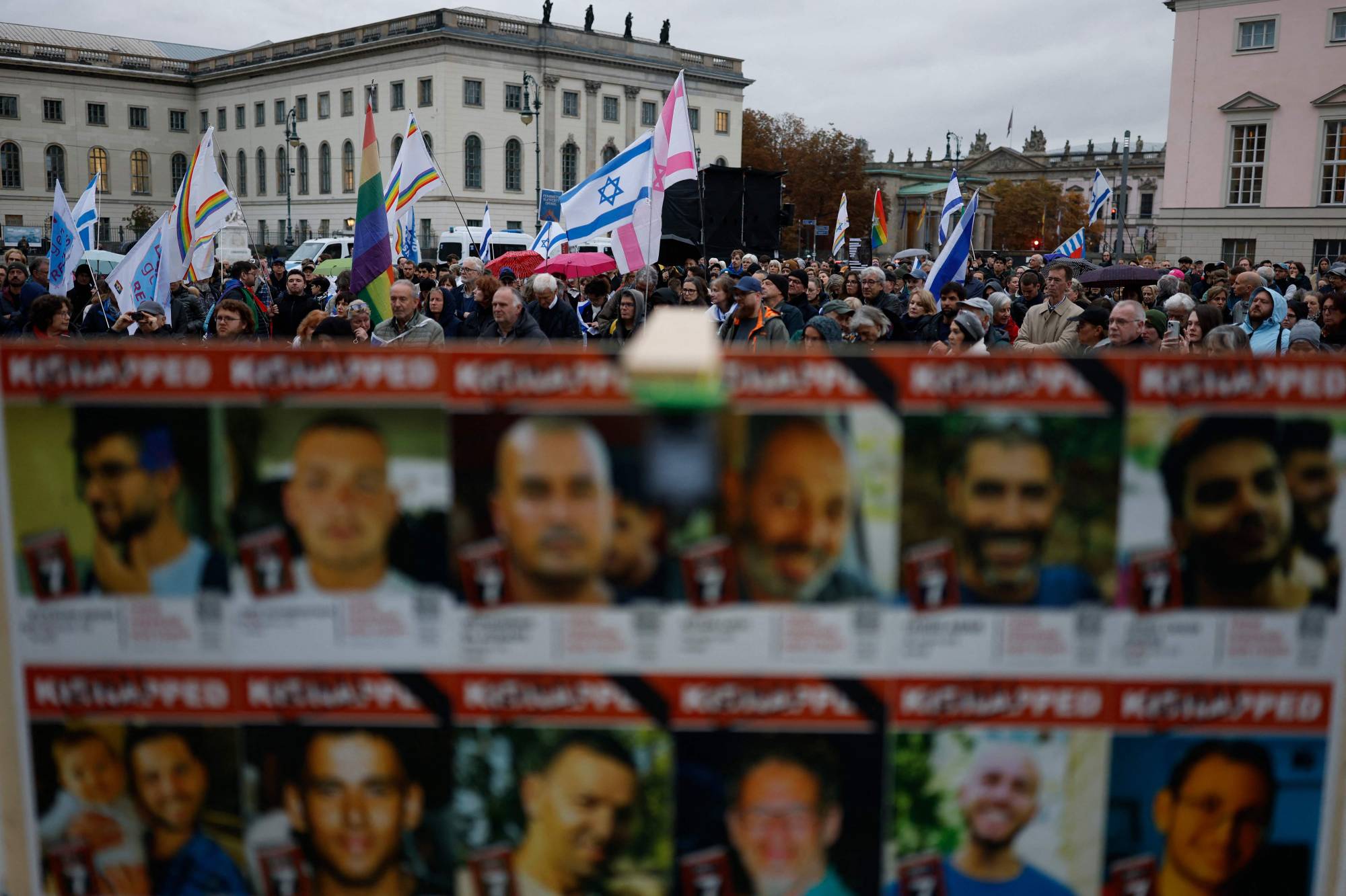 İnsanlar, 7 Ekim 2025'te İsrail'e yönelik gerçekleştirilen saldırının ikinci yıldönümünü anmak için Berlin'deki Bebelplatz Meydanı'nda İsrailli rehinelerin fotoğraflarının arkasında bir nöbet tutuyor (AFP)