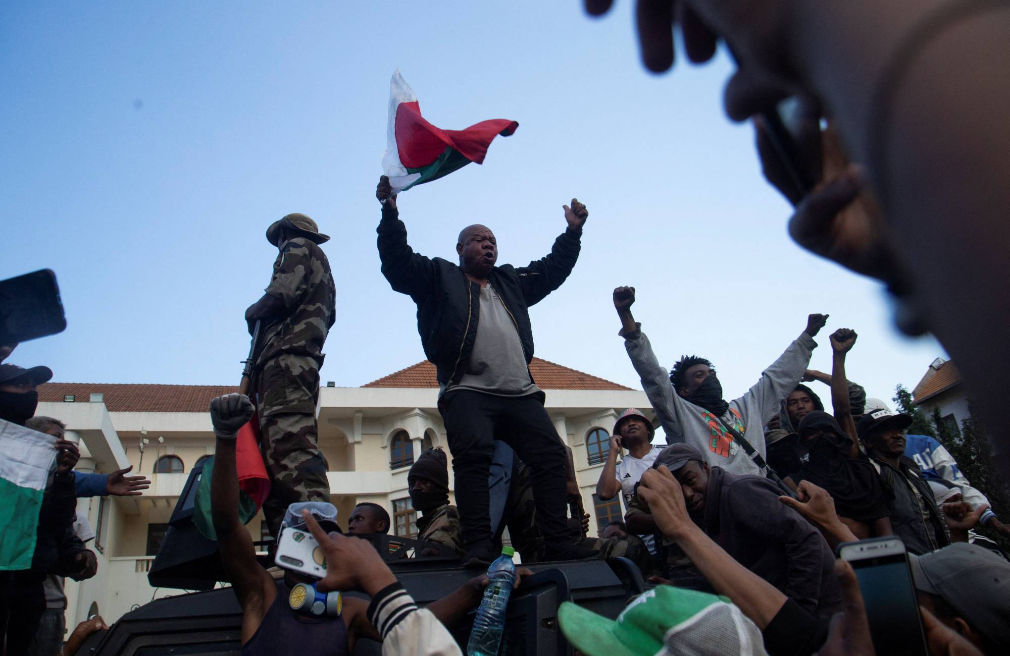 Başkent Antananarivo'daki protestolar sırasında bir protestocu Madagaskar bayrağı elinde bir askeri aracın üzerine çıkıyor (Reuters)