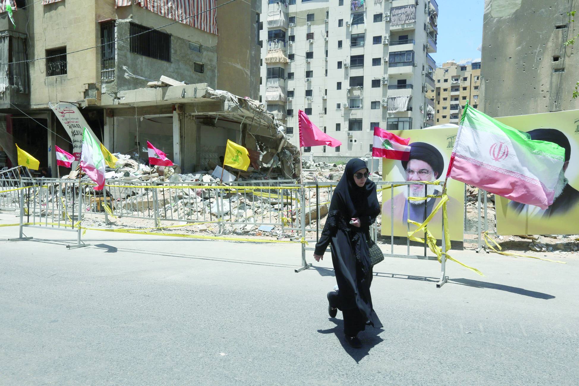 Beyrut'un güney banliyölerinde İsrail tarafından bombalanan bir bölgede Lübnan, İran ve Hizbullah bayrakları (EPA)
