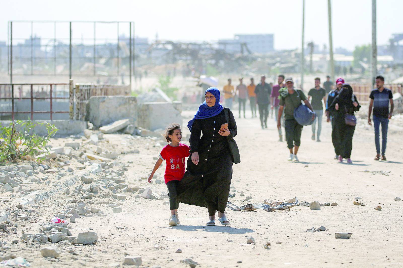 Bir kadın, Gazze Şeridi'nin merkezindeki Nuseyrat'tan Netzarim geçiş noktası üzerinden Gazze Şehri'ne doğru kız çocuğuyla birlikte yürüyor (AFP)