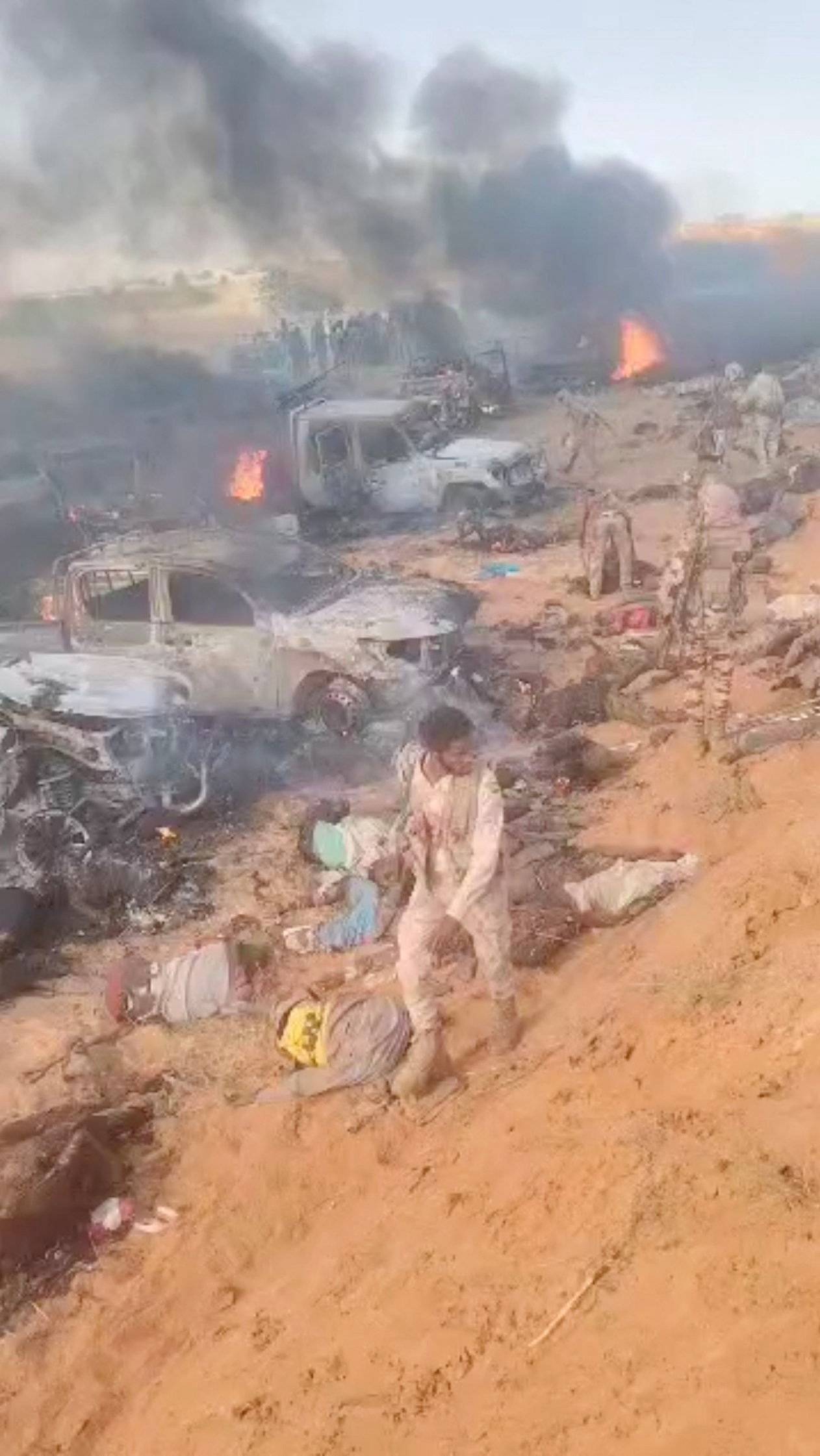 El-Faşir yakınlarında düzenlenen bir saldırı sırasında silahsız insanların cesetleri ve yanmış araçların arasında yürüyen Hızlı Destek Kuvvetleri (HDK) milisleri (Reuters)