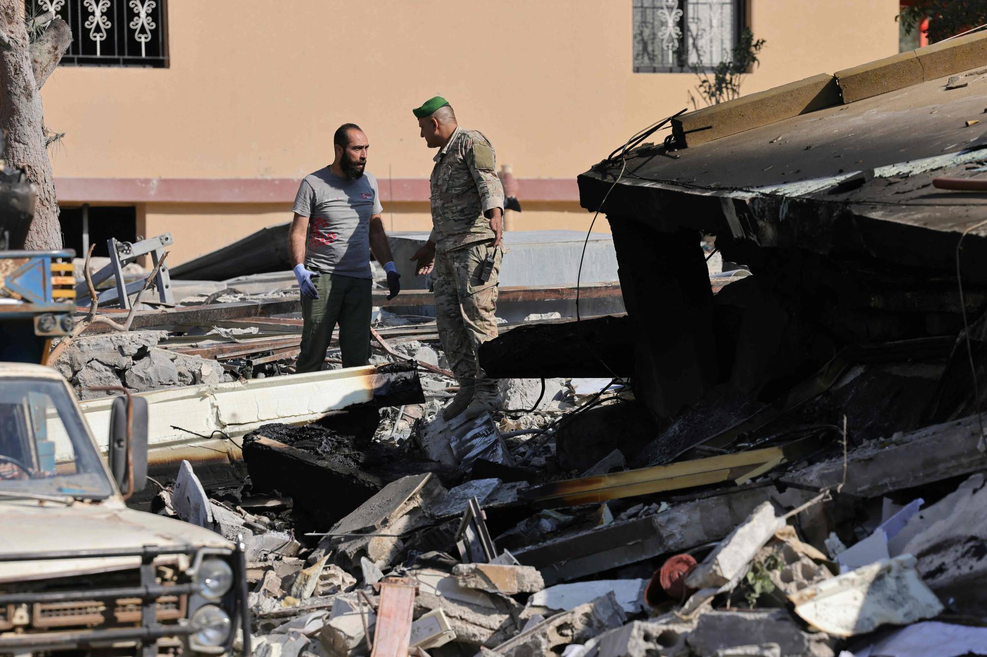 Lübnan'ın güneyindeki Taybe kasabasında İsrail hava saldırısının olduğu yerde bir Lübnanlı asker ve vatandaş (AFP)