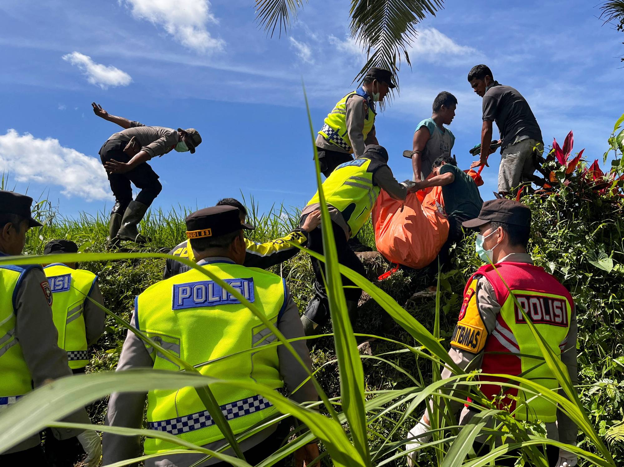 Kurtarma ekipleri, Batang Anai'de şiddetli yağışların ardından meydana gelen ani sellerden etkilenen bir bölgede operasyon sırasında bir kurbanın içinde bulunduğu ceset torbasını pirinç tarlasında taşıyor (Reuters)