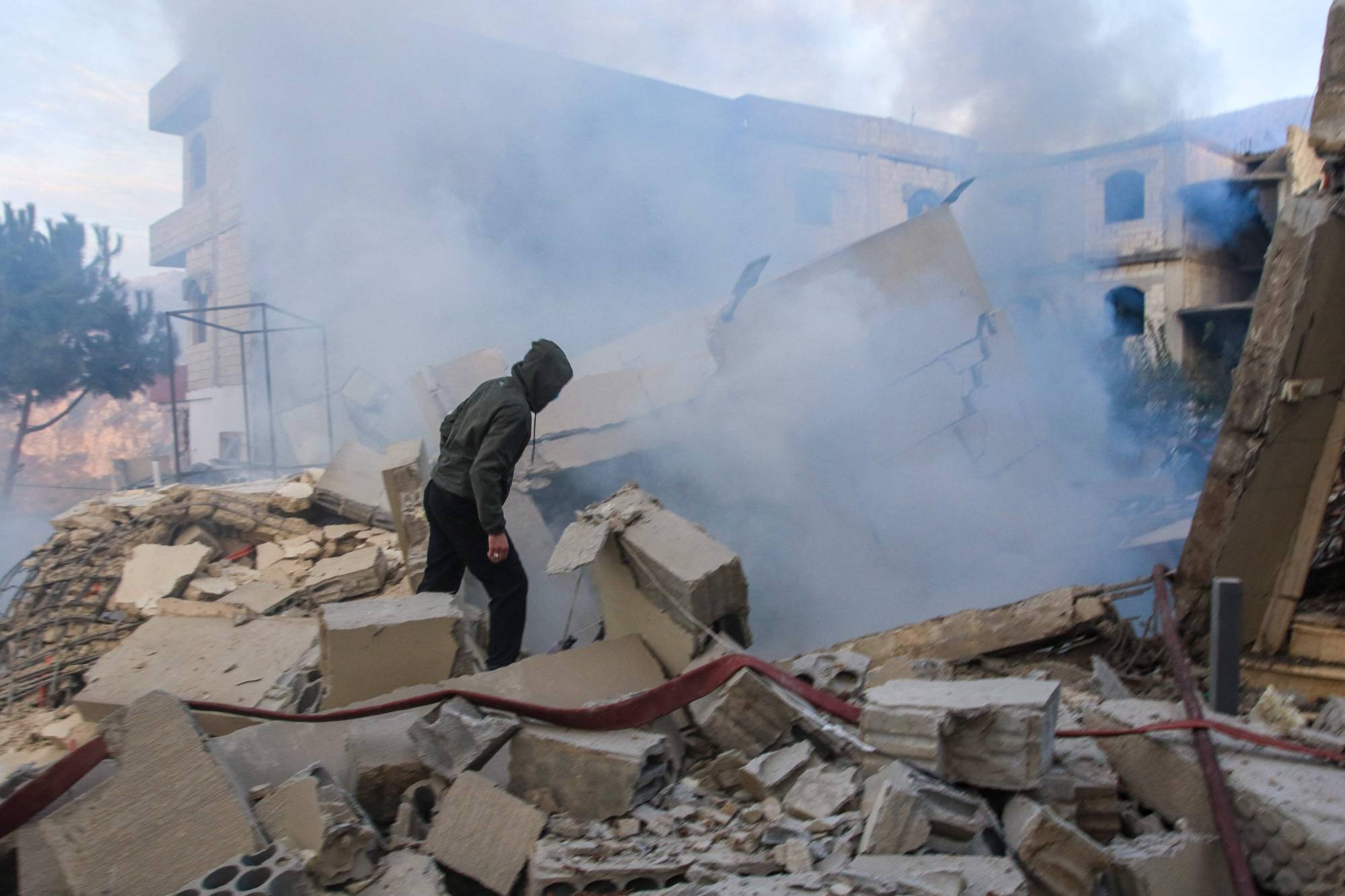 4 Aralık'ta Lübnan'ın güneyindeki Ceba köyünü hedef alan İsrail hava saldırısının ardından bir kişi hasarı inceliyor (AFP)