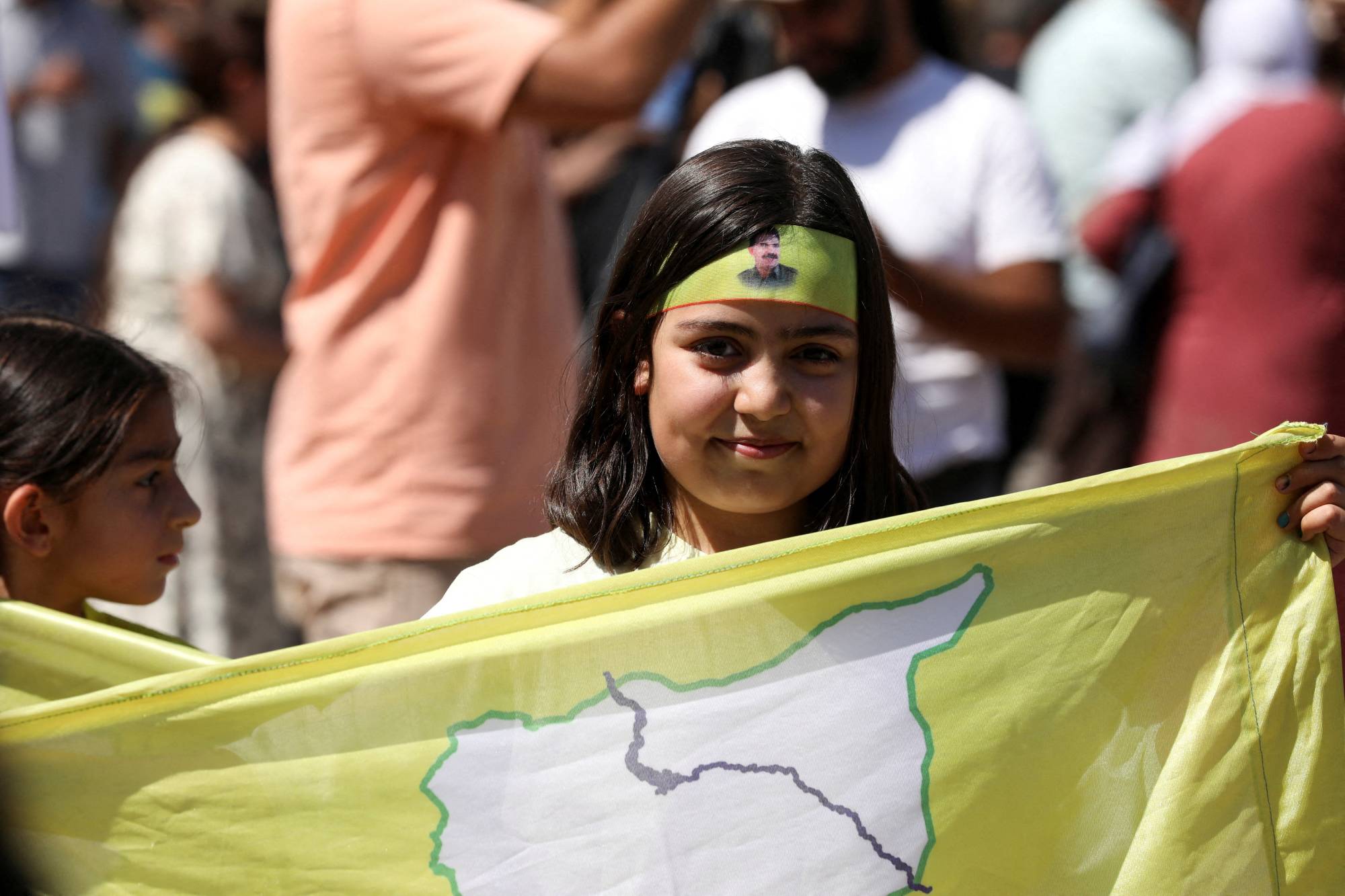 Suriye'nin Kamışlı kentinde düzenlenen gösteride bir kız çocuğu SDG bayrağını taşıyor... 17 Eylül 2025 (Reuters)