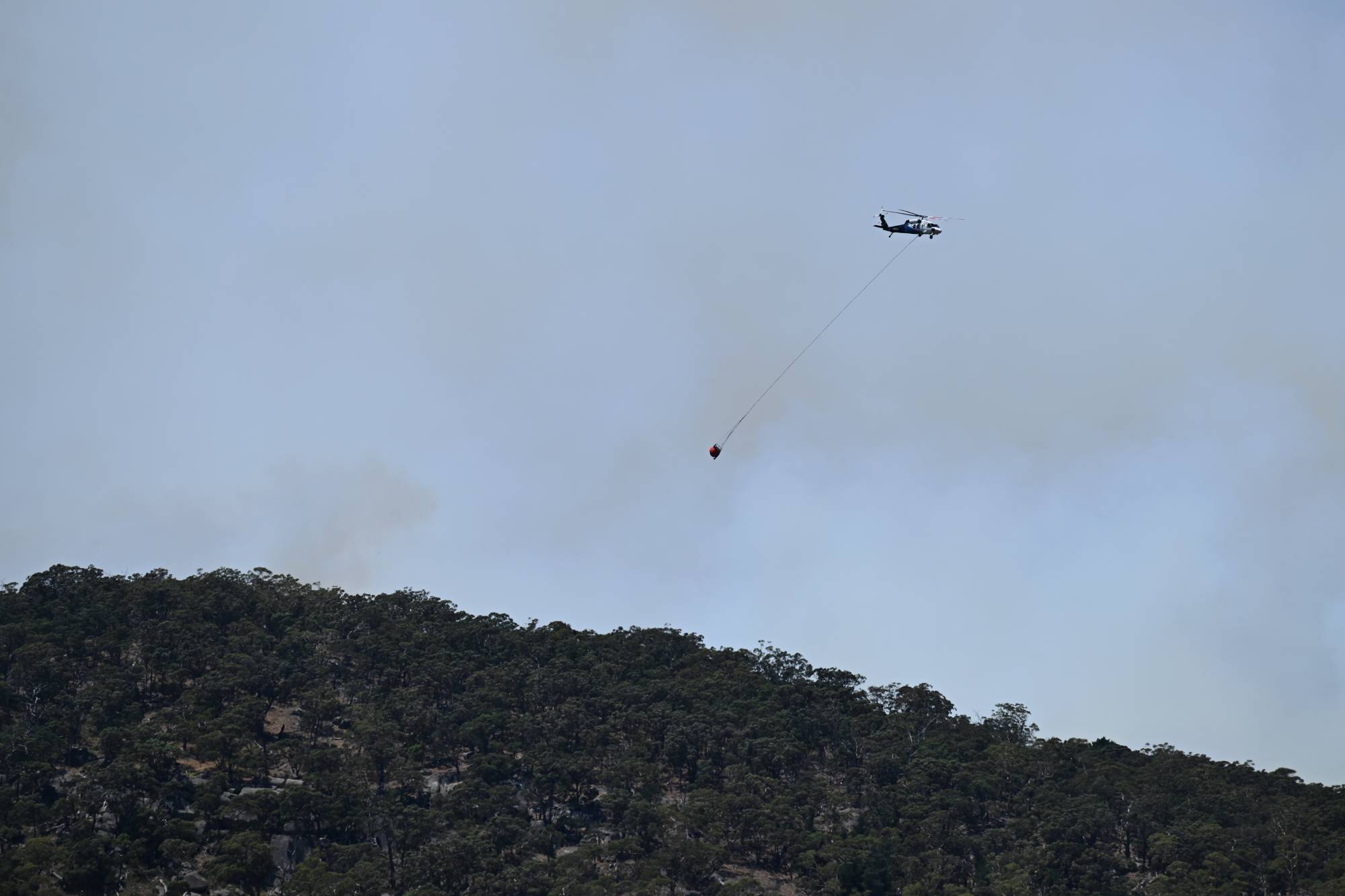 Avustralya'nın Victoria eyaletindeki Harcourt'ta alevler içinde kalan bir ormana helikopterle su bırakılıyor. (EPA)