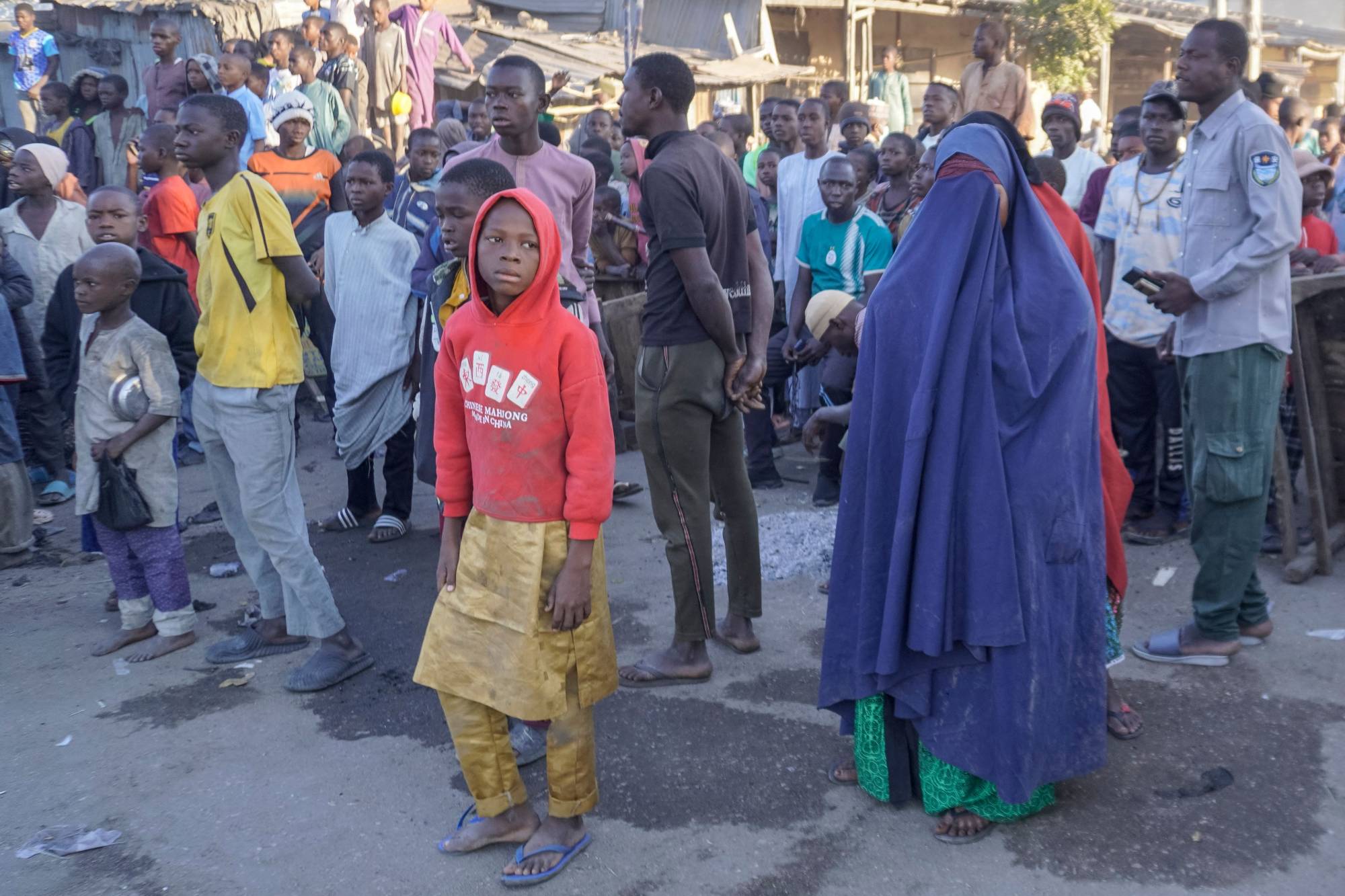 Nijerya'nın kuzeydoğusundaki Maiduguri şehrinde bulunan Gamboru pazarındaki bir camiye düzenlenen bombalı saldırının ardından olay yerinin yakınında toplanan halk, (Arşiv-AFP)