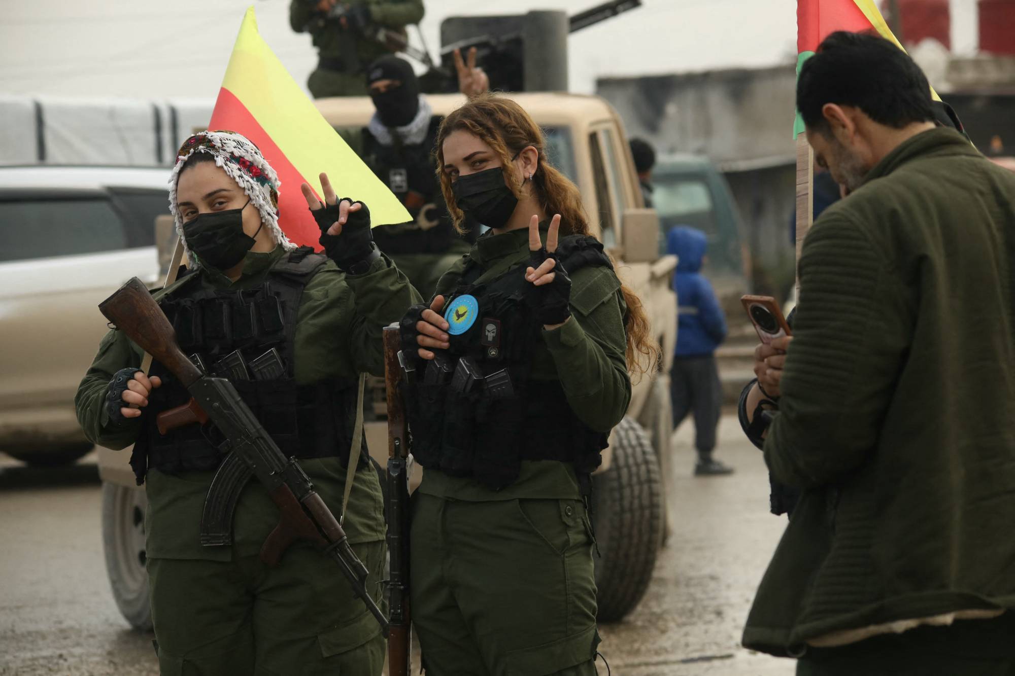 SDG'den iki kadın savaşçı, Suriye'nin kuzeydoğusundaki Haseke'de Suriyeli Kürtlerin düzenlediği bir gösteride  zafer işareti yapıyor (AFP)