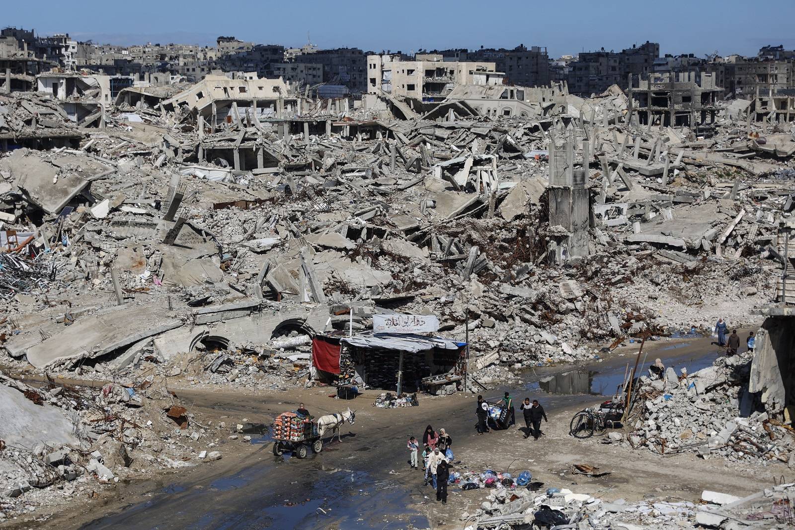  Gazze şehrinin Şeyh Rıdvan mahallesinde yıkılmış binaların enkazı arasında ilerleyen Filistinliler (AFP)