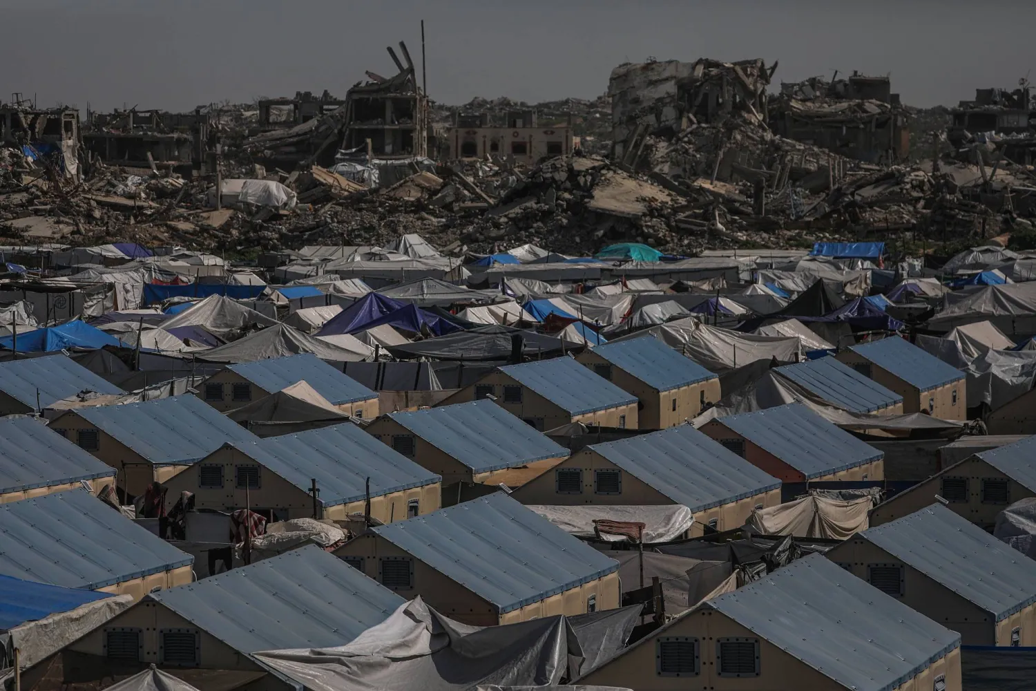 İsrail'in Deyr el-Belah'ta serbest bıraktığı kimliği belirsiz Filistinlilerin toplu mezarındaki cesetlerin yanından geçen vatandaşlar (Reuters)